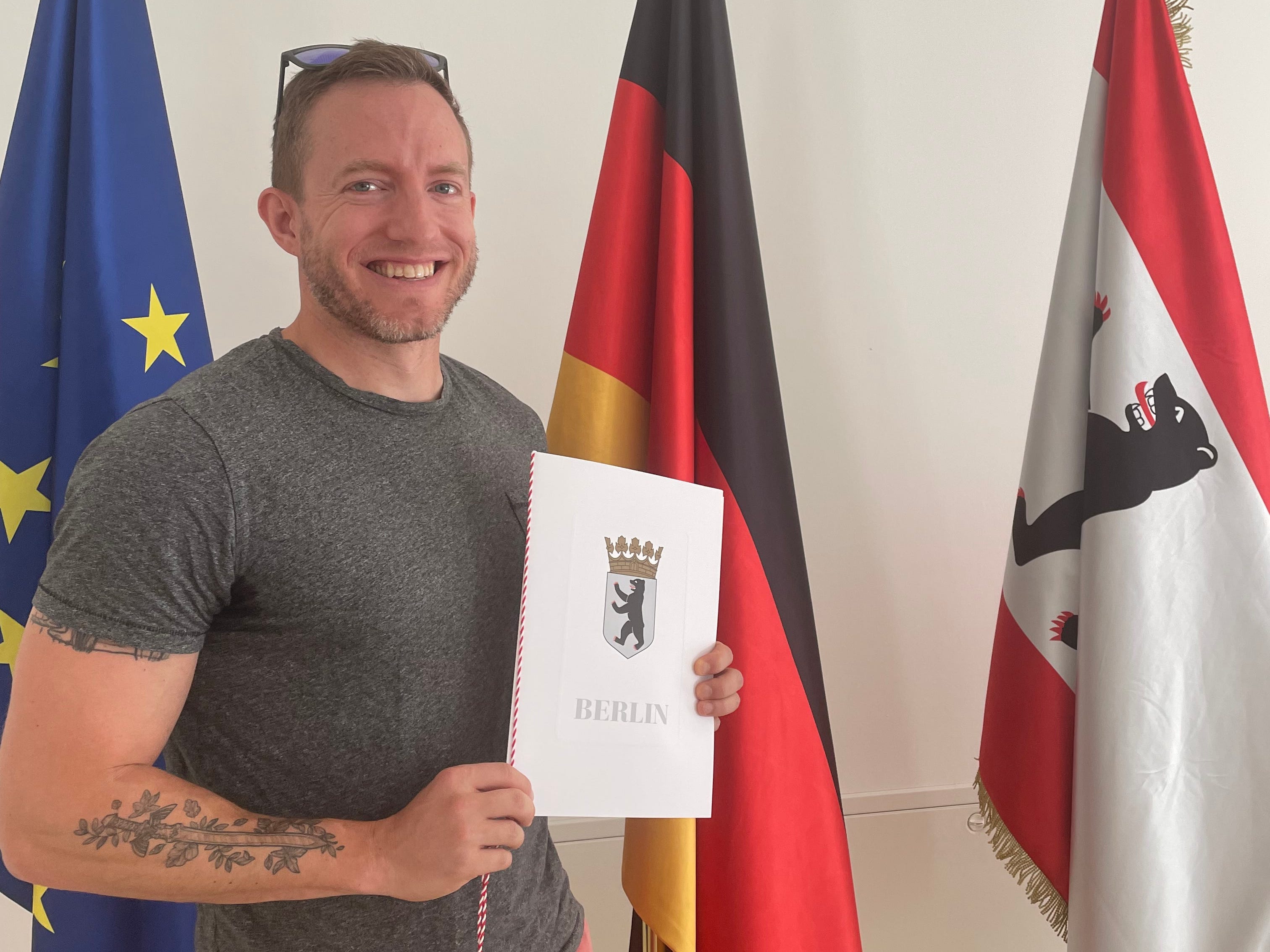 Man holding paperwork in front of German flag
