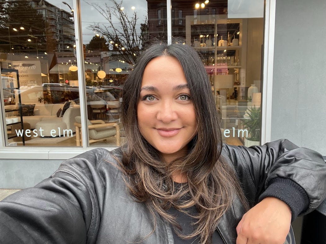 Carmen takes a selfie in front of a West Elm store.