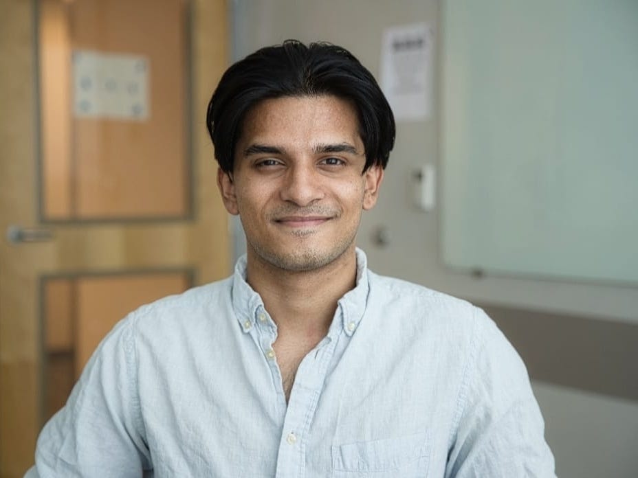 man with dark hair and button up shirt posing for a headshot.