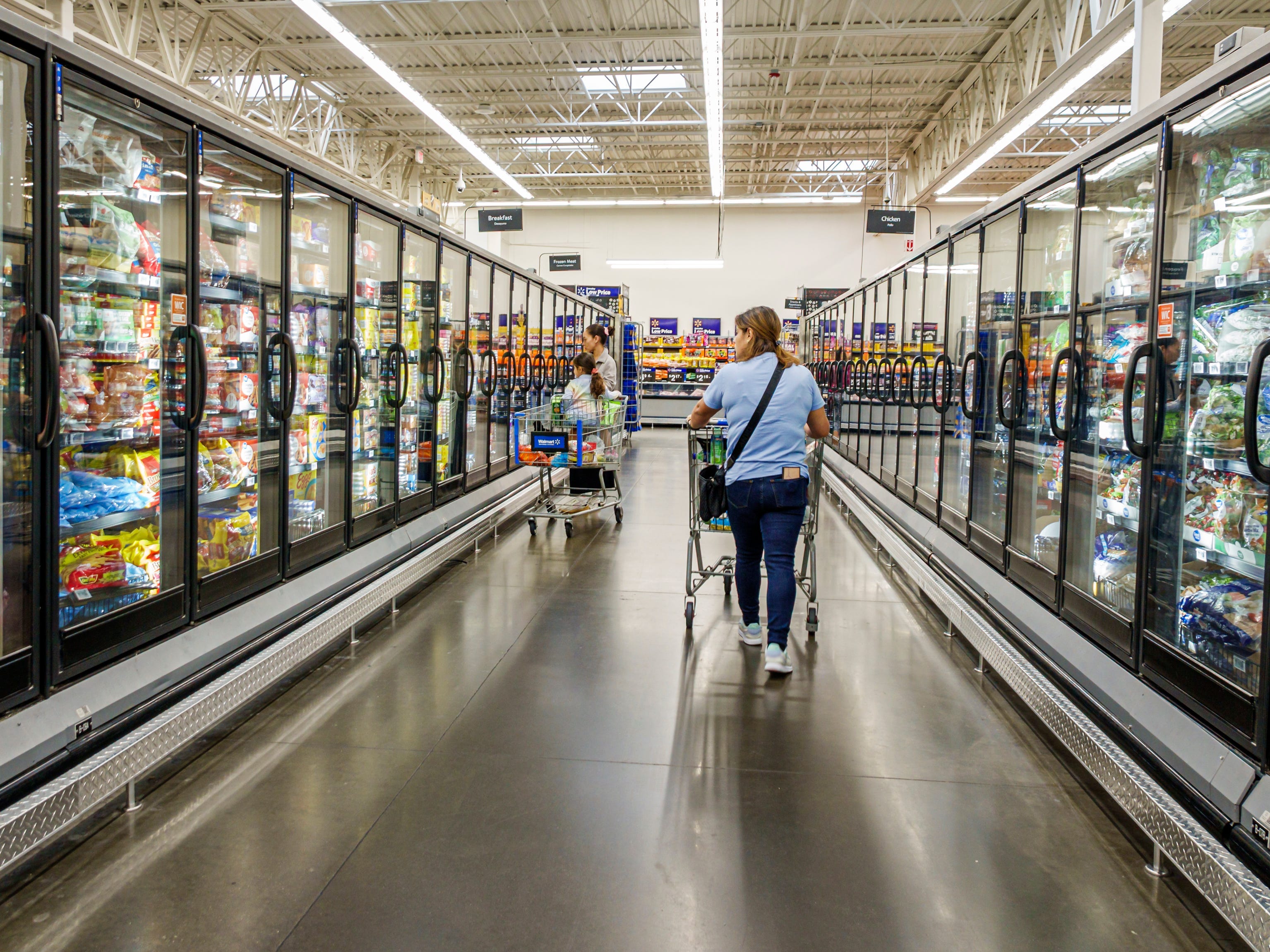 People with shopping carts in a frozen foods aisle