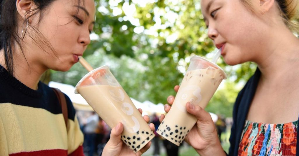 Two Asian girls drinking bubble tea in the park