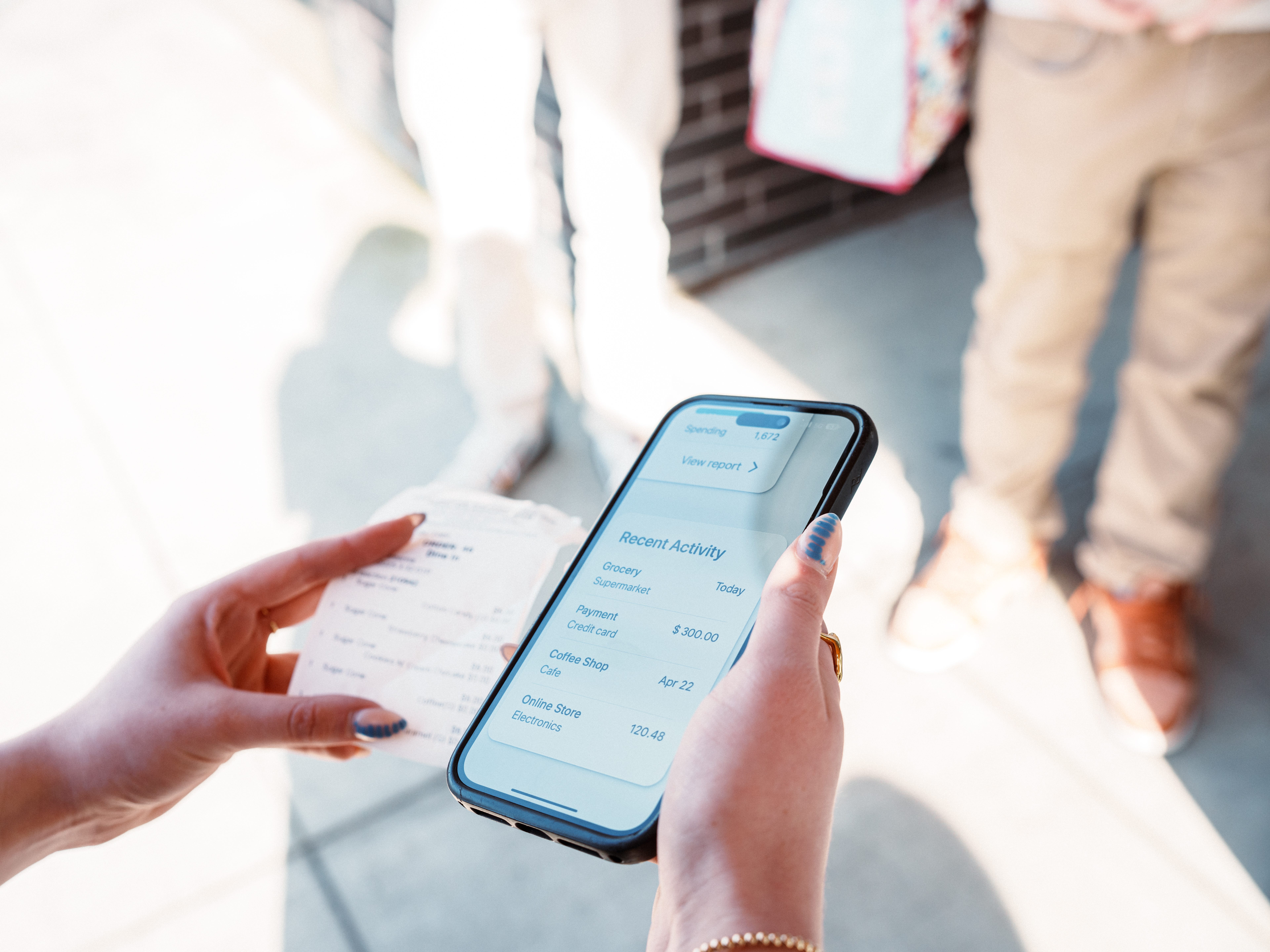a woman holding a receipt and her phone with more transactions