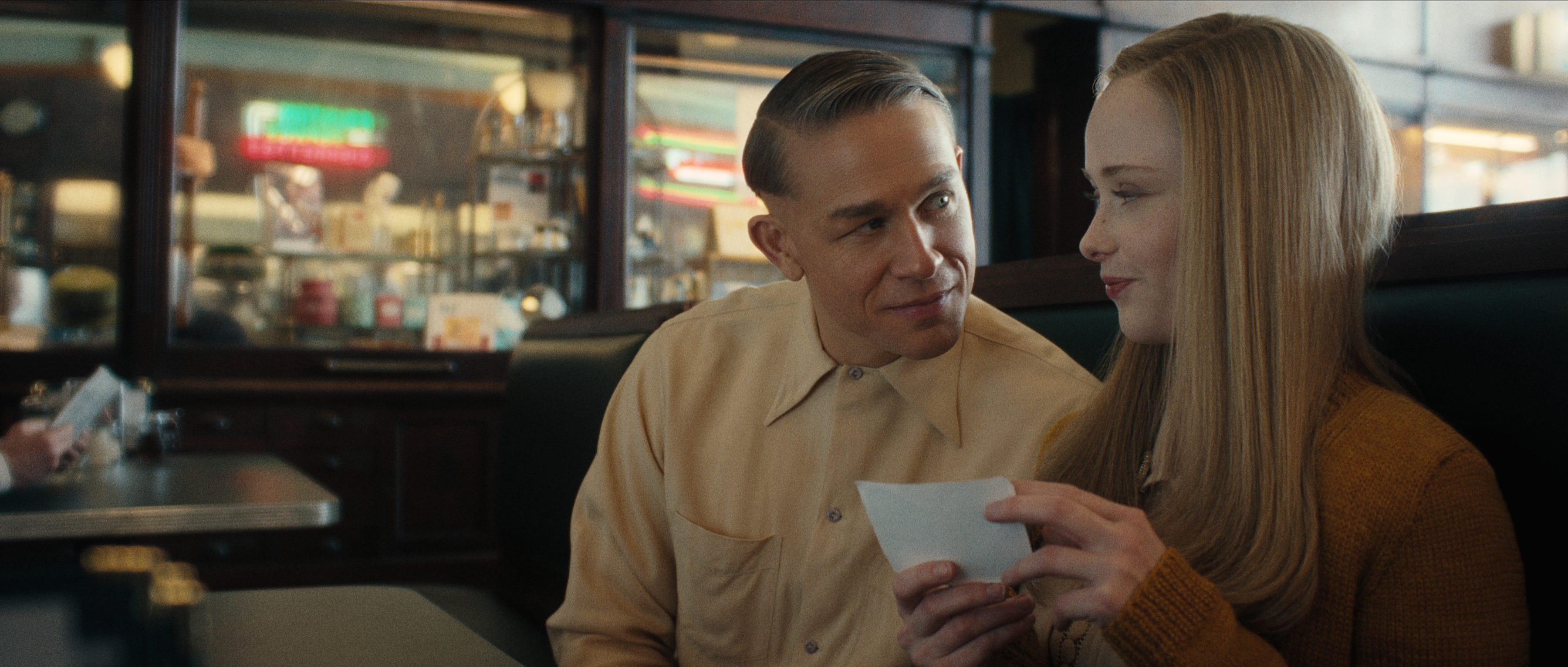 Charlie Hunnam as Ed Gein sitting in a booth with a girl