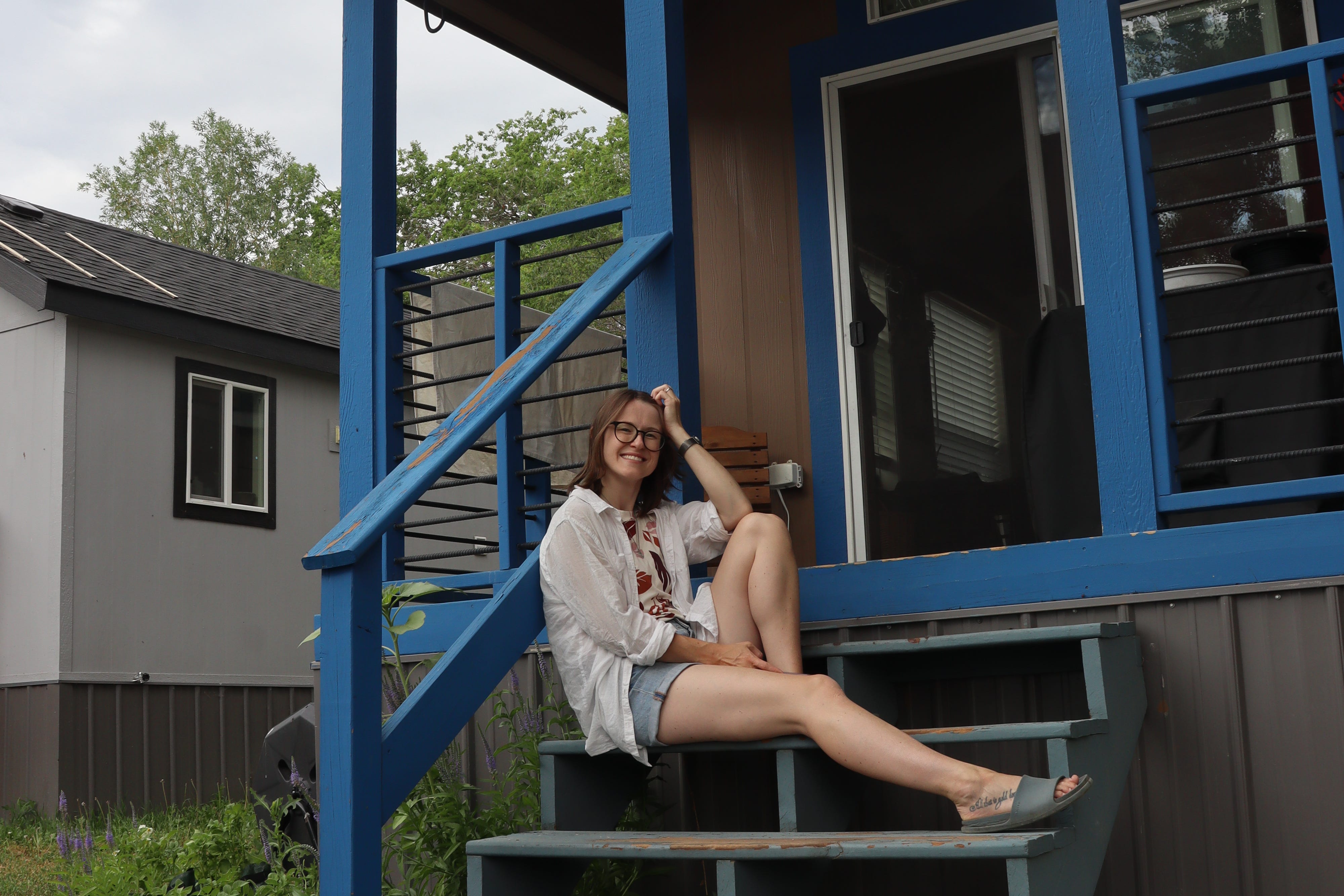 Author Amber McDaniel sitting on steps of tiny home