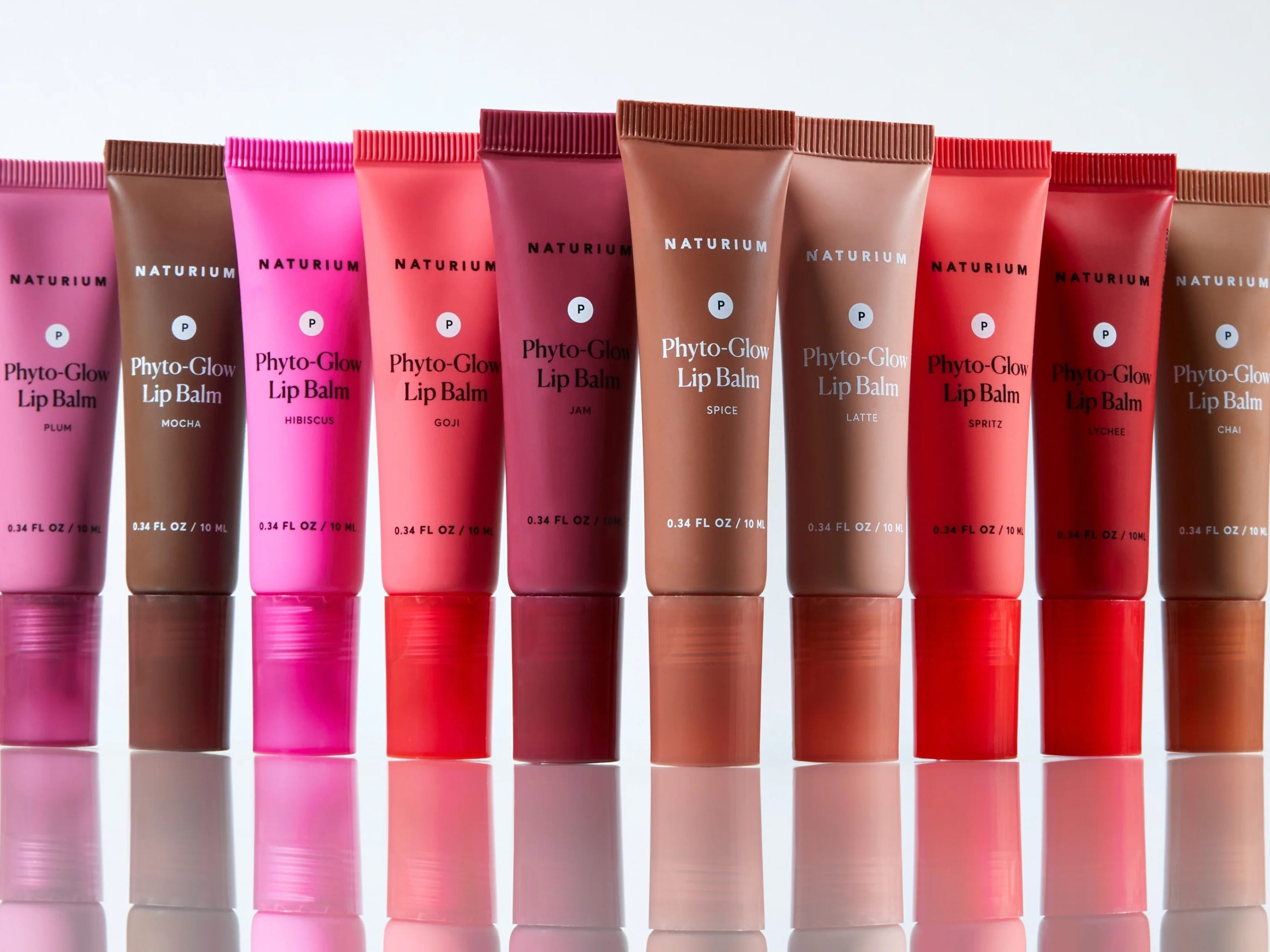 A group of 13 Naturium Phyto-Glow lip balms arranged in a line.