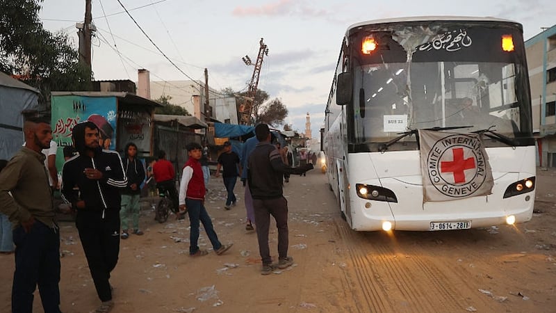 Palestinian youths watch as a bus bearing the emblem of the International Red Cross moves towards the eastern Gaza Strip from Khan Yunis in the south of the besieged territory on October 13, 2025, ahead of the release of Israeli hostages held by Hamas since the October 7 attacks two years ago. On the other side, a Red Cross convoy is on its way to pick up a first batch of Israeli hostages to be freed by Hamas as part of a Gaza ceasefire deal announced by US President Donald Trump earlier this month, the Israeli military said on October 13.