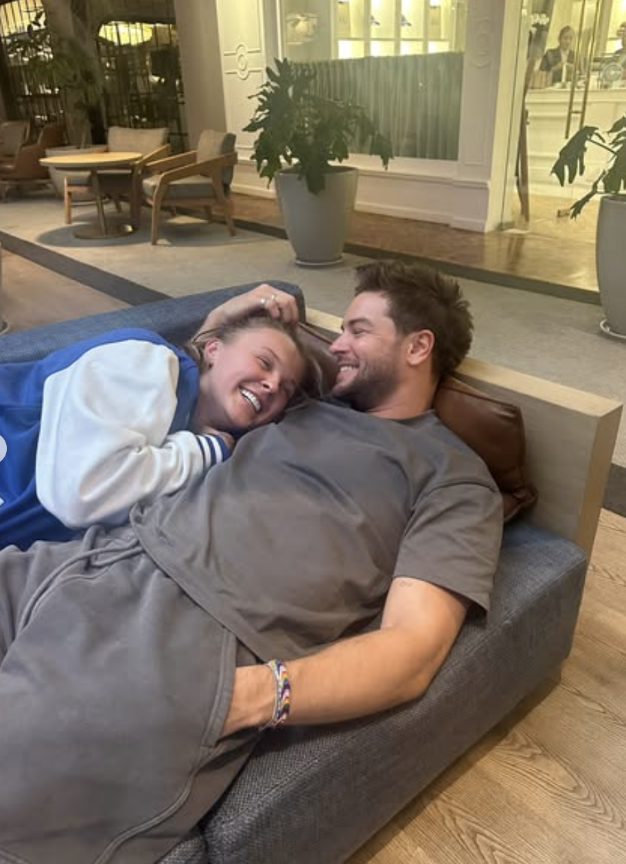 Jojo Siwa and Chris Hughes lying together on a couch.
