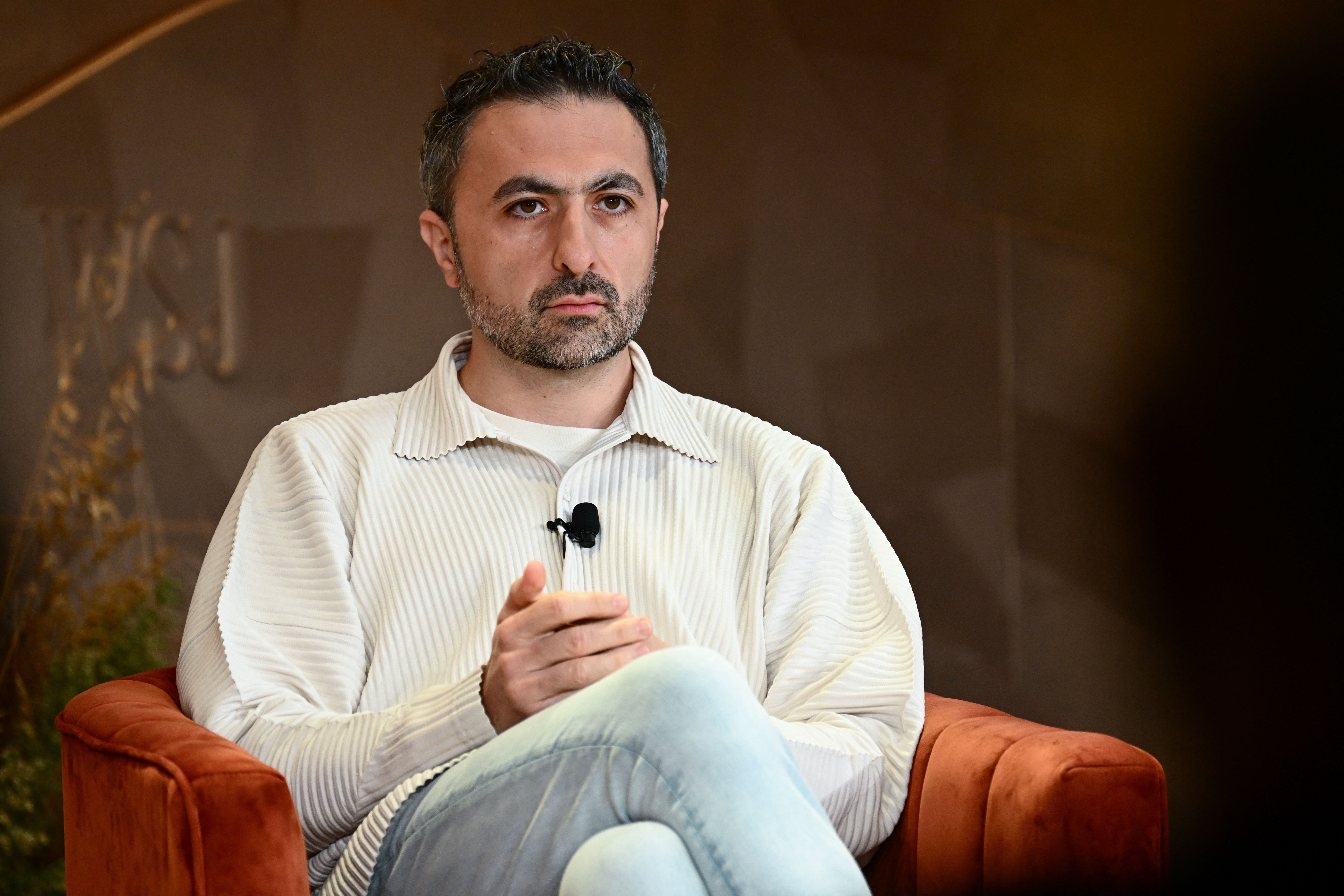Mustafa Suleyman wearing a cream shirt with blue jeans