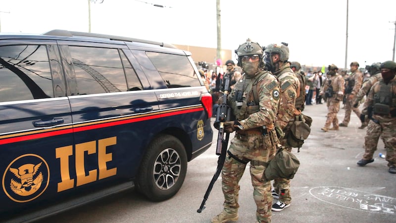 Immigration and Customs Enforcement (ICE) agents armed with less-lethal weapons gather outside an ICE processing center during a protest in Broadview, Illinois