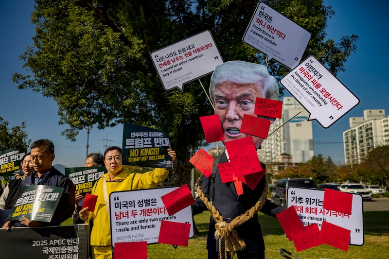 A demonstrator wears a paper cutout of U.S. President Donald Trump during a protest at the entrance of Bomun Lake Resort, the main venue of 2025 APEC Economic Leaders' Meeting on October 29, 2025 in Gyeongju, South Korea.
