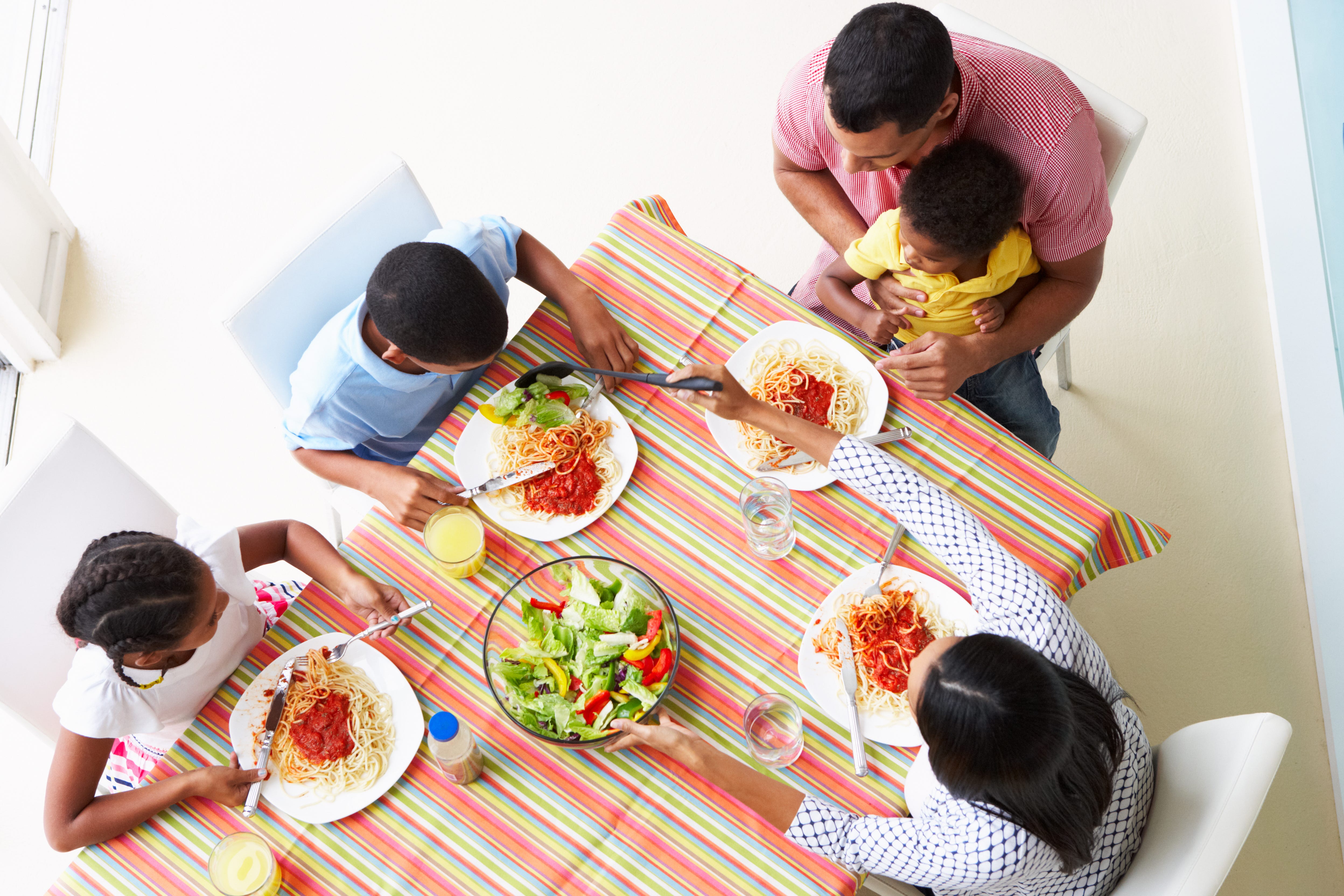 A family is shown from overhead enjoying a spaghetti and salad dinner.