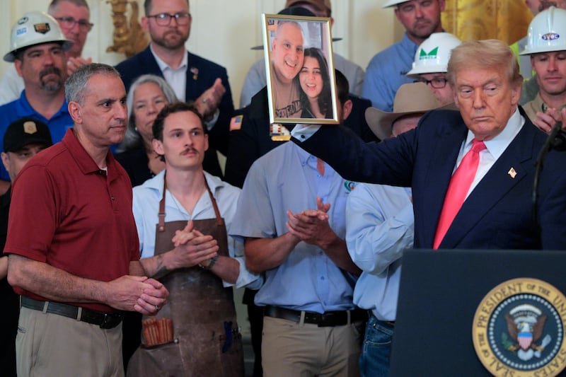 U.S. President Donald Trump holds up a photograph of Joe Abraham (L) and his daughter Katie