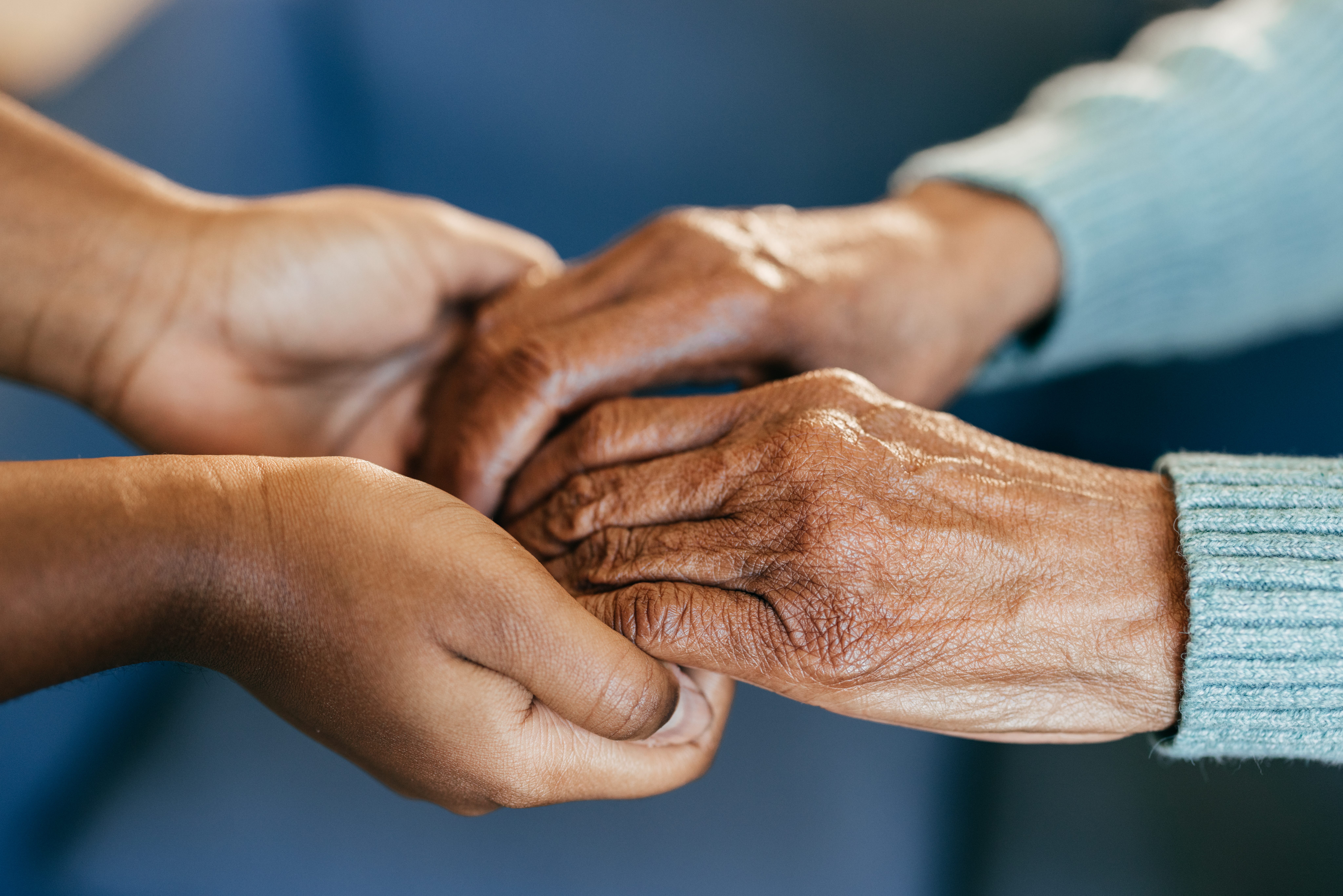A granddaughter embraces her grandmother's hands.