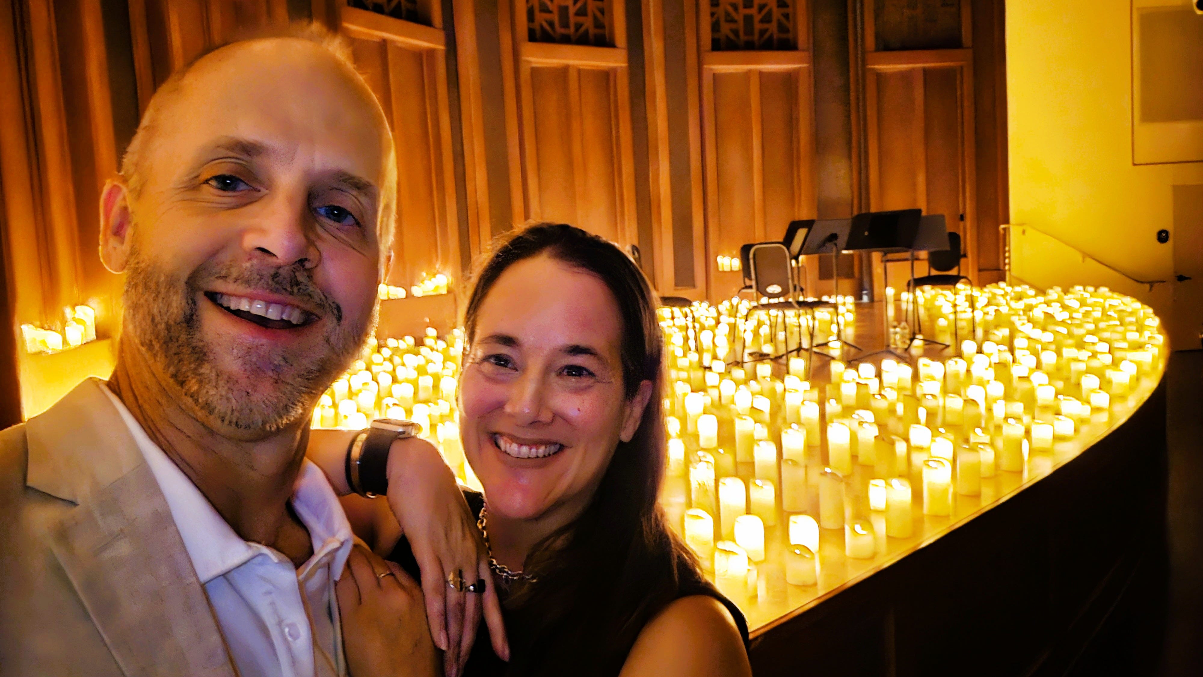 The author and her husband pose in front of a stage lit with cancles