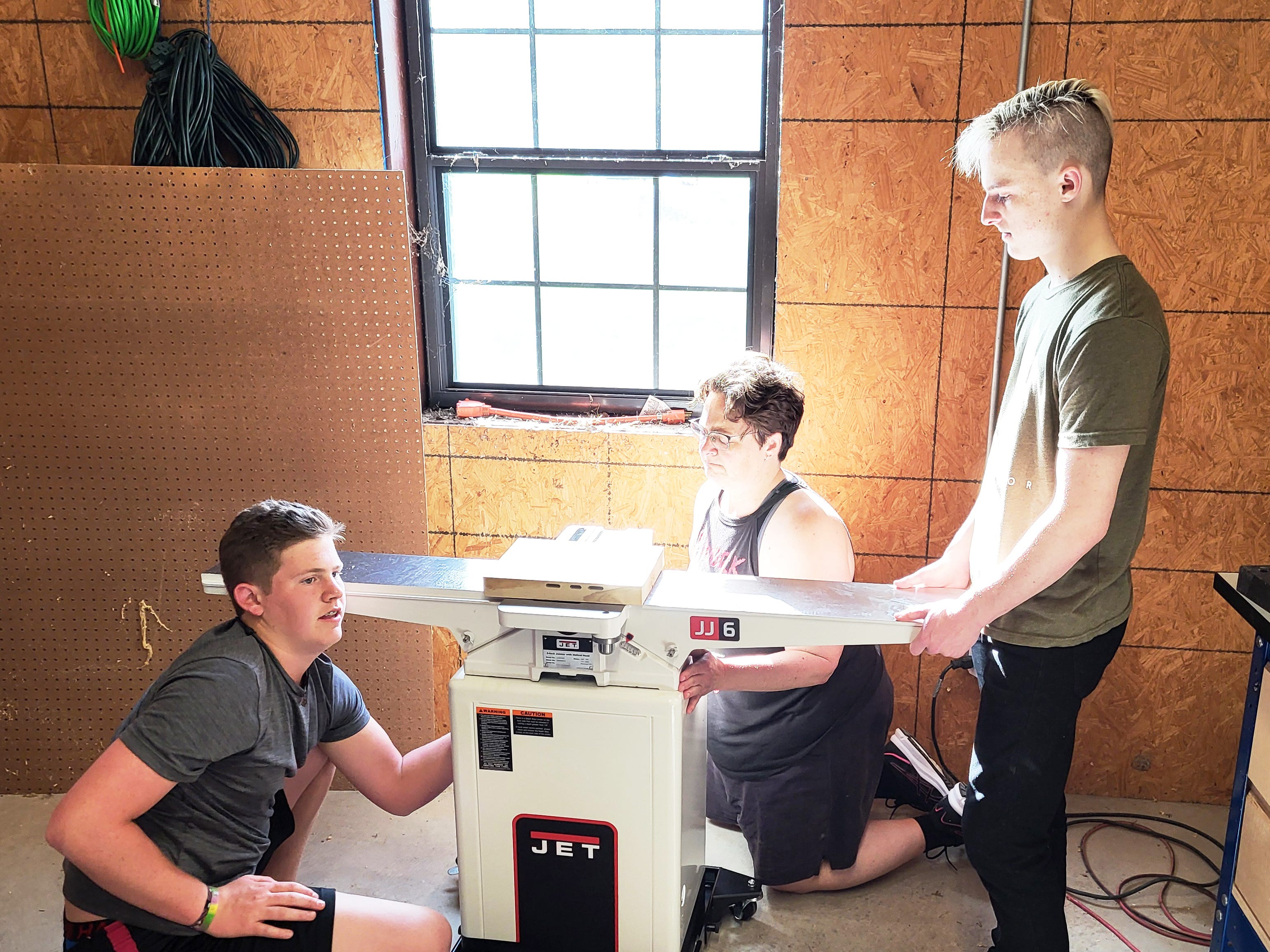 Three adult kids building a tool