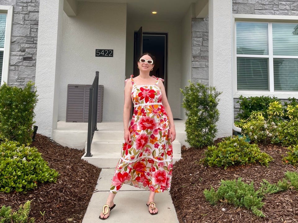 Author Simone Paget wearing sunglasses, standing in front of villa entrance