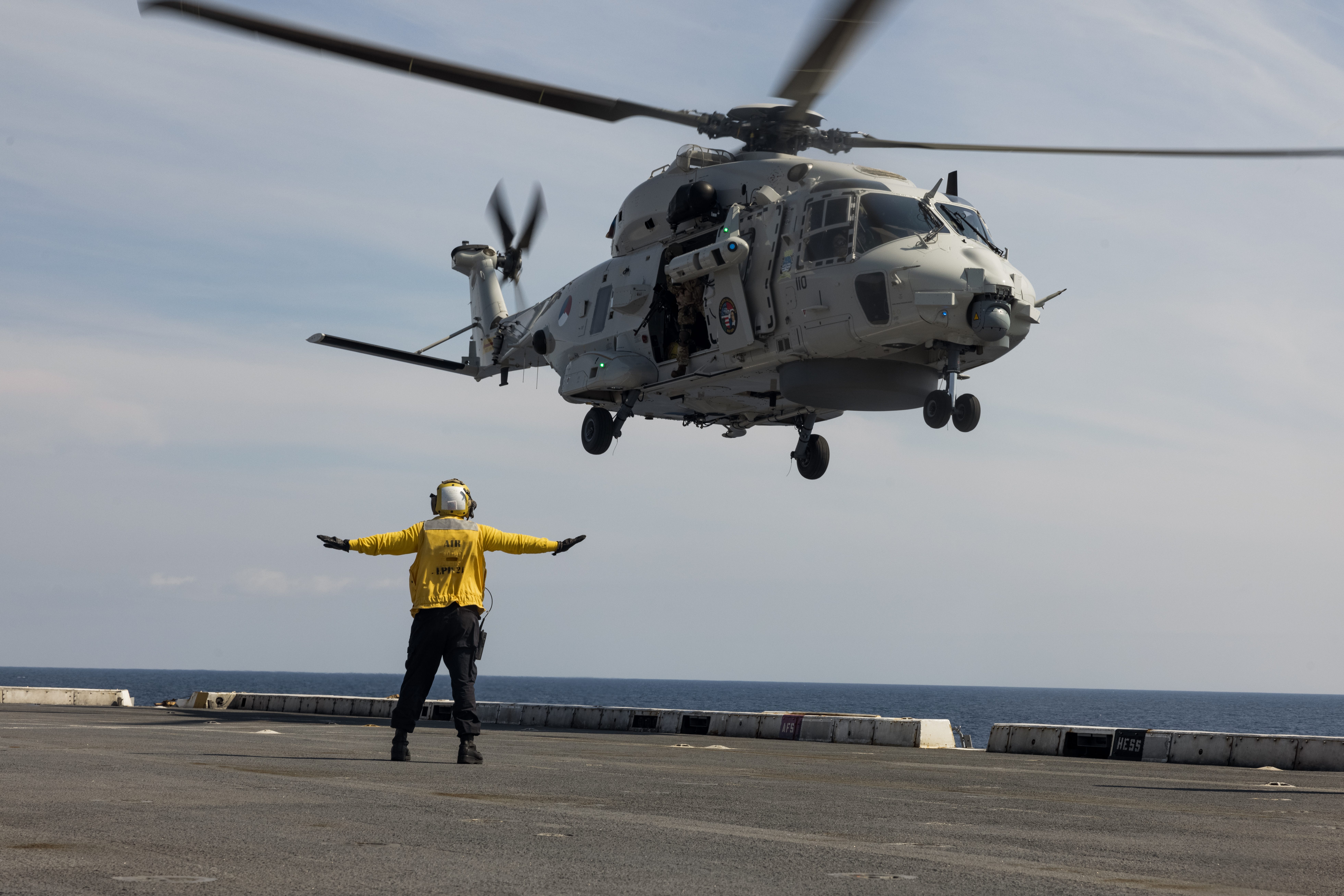the San Antonio-class amphibious transport dock ship USS New York (LPD 21), signals a Royal Netherlands Navy NH90 helicopter from the Rotterdam-class landing platform dock HNLMS Johan de Witt (L 801) during exercise Atlantic Alliance 2025 (AA25) aboard the New York, July 6, 2025.