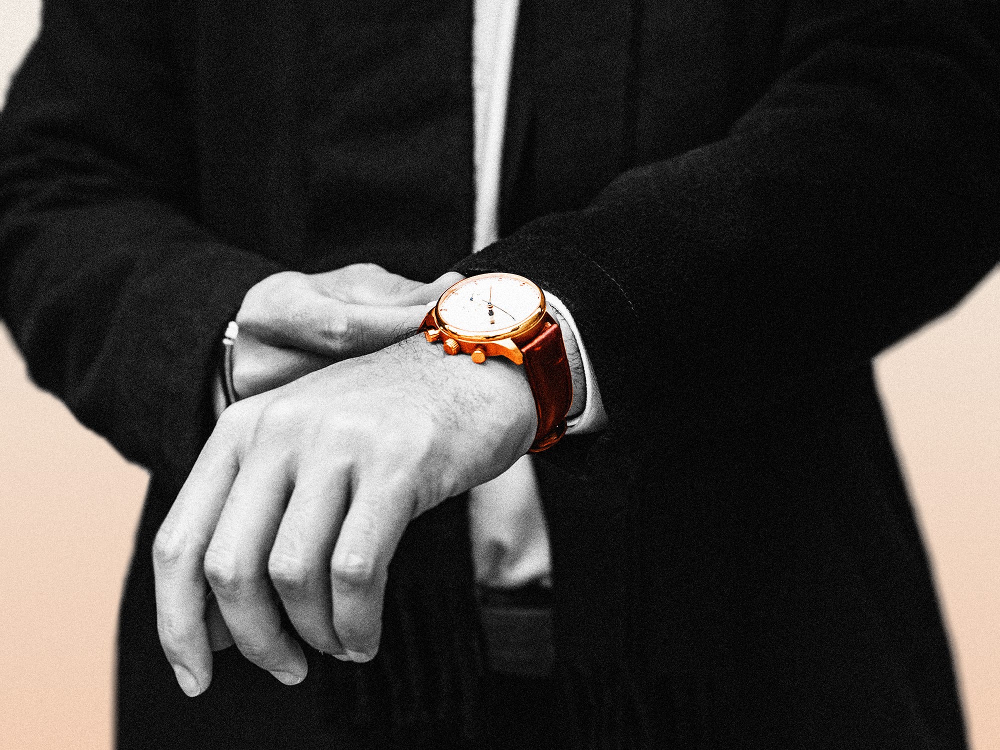 A man in a suit with his wristwatch in the center of the composition