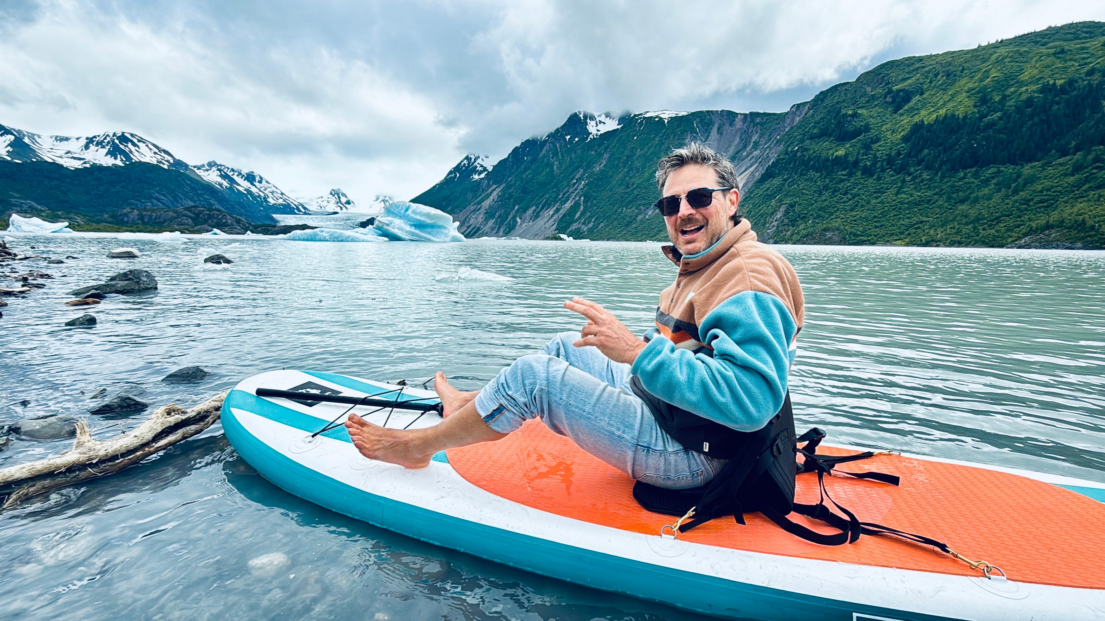Author Ash Jurberg sitting on kayak in glacier lake, smiling