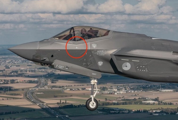 A grey fighter jet in the sky with a new drone-shaped marking under the cockpit circled in red