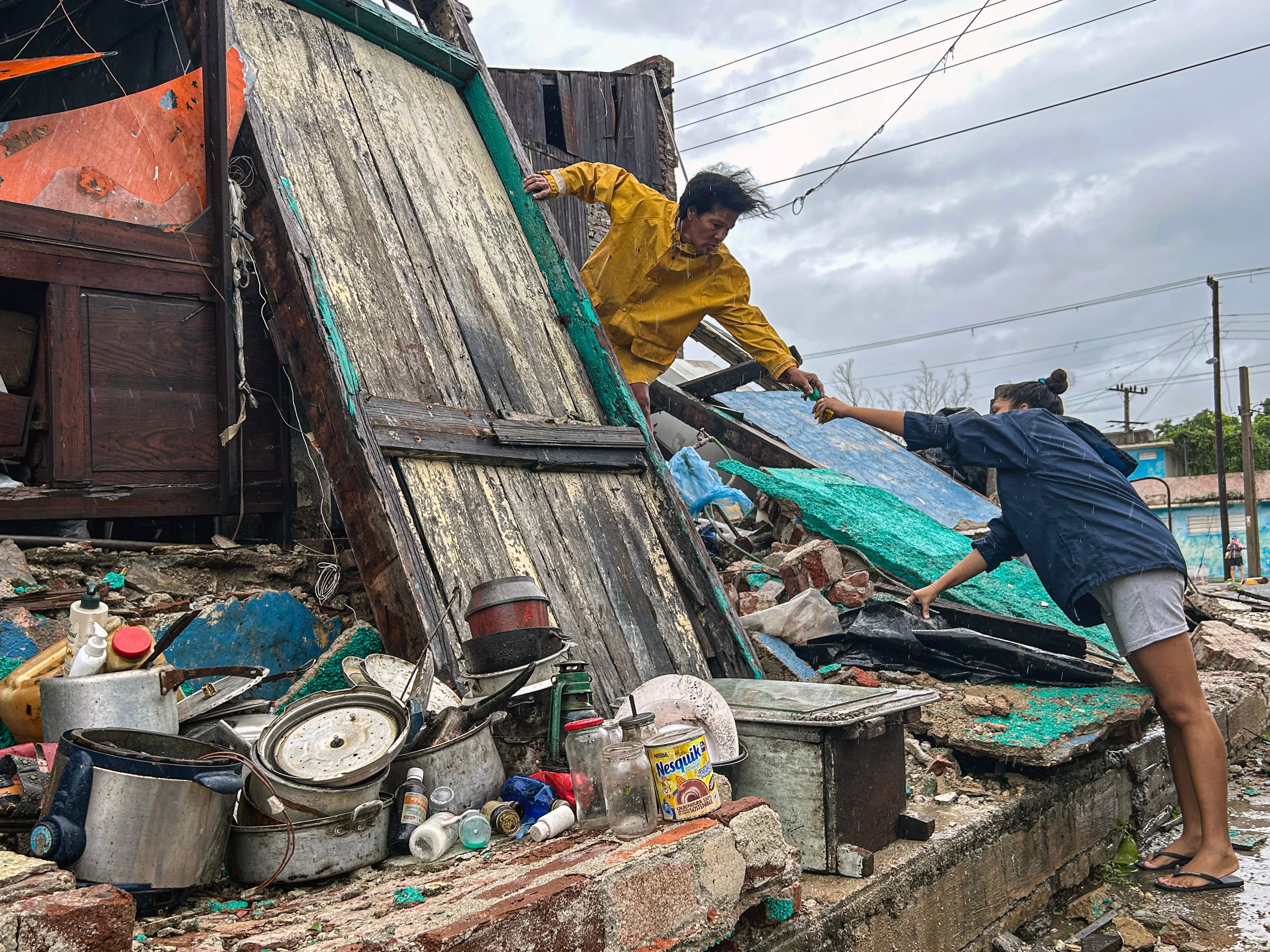 A family salvages belongings from the rubble of their home after it collapsed during Hurricane Melissa's passage through Santiago de Cuba, Cuba, on October 29, 2025.