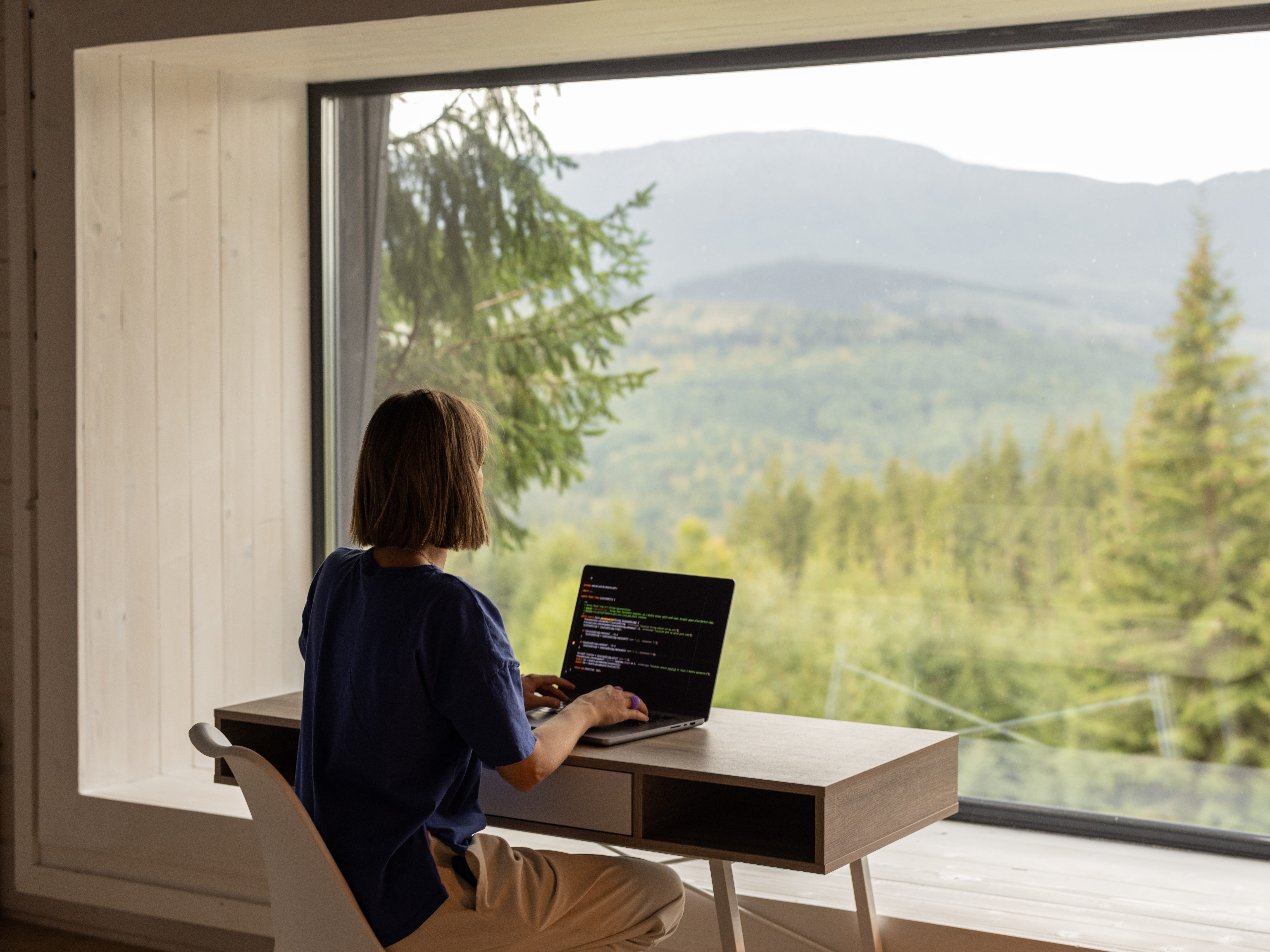 Woman working on computer in front of window