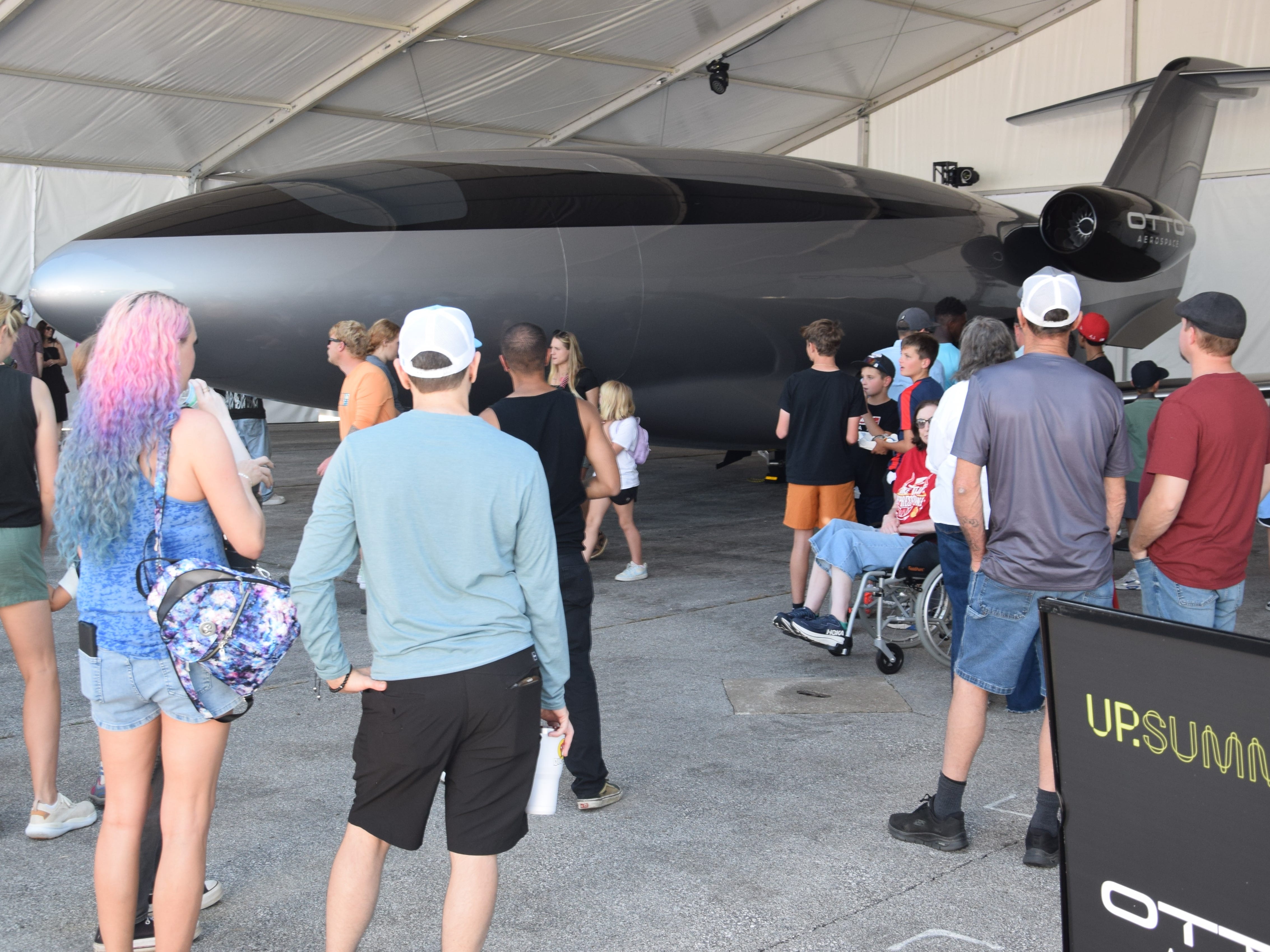 People standing around a black and gray full-scale mockup of Otto Aerospace's Phantom 3500 private jet.
