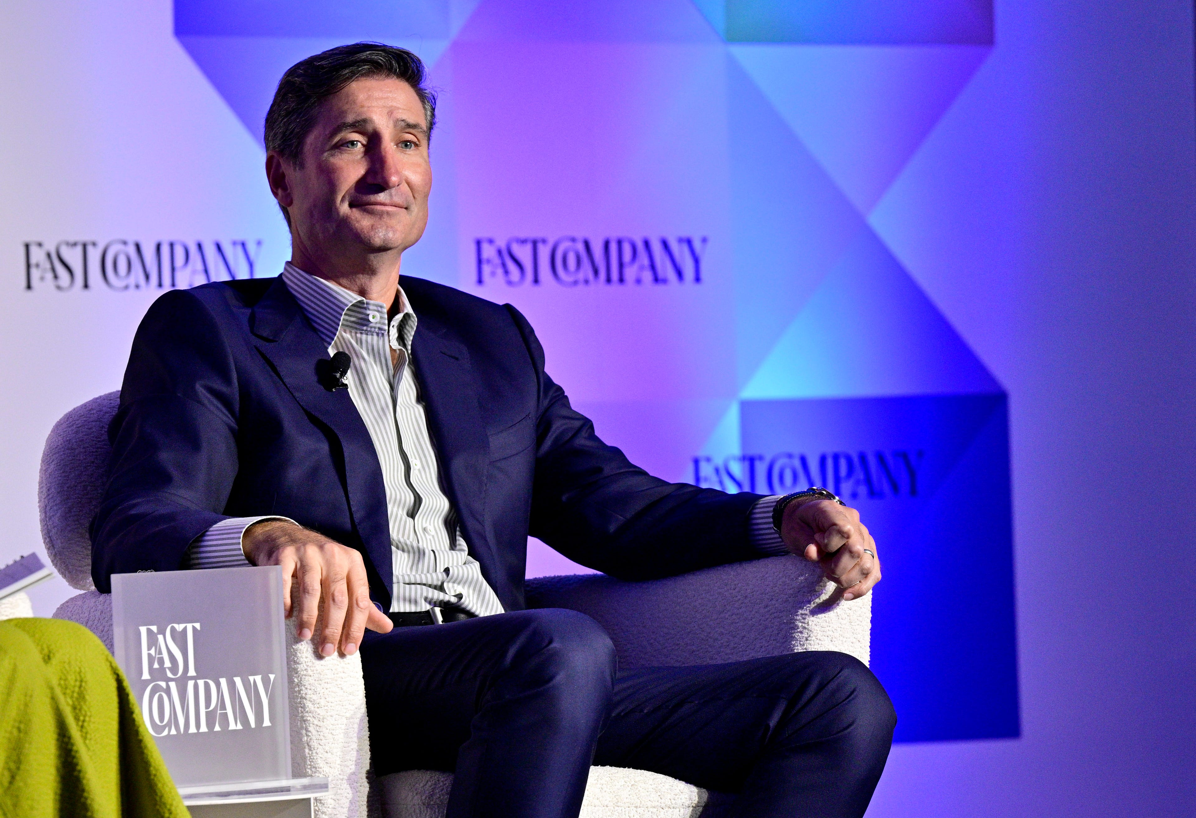 Starbucks CEO Brian Niccol sits in a chair onstage during a Fast Company conference.