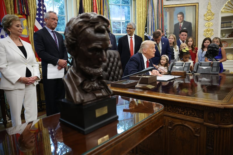 U.S. President Donald Trump (C) speaks before signing executive orders with Education Secretary Linda McMahon (L) and Health and Human Services Secretary Robert F. Kennedy Jr. (2nd L) in the Oval Office