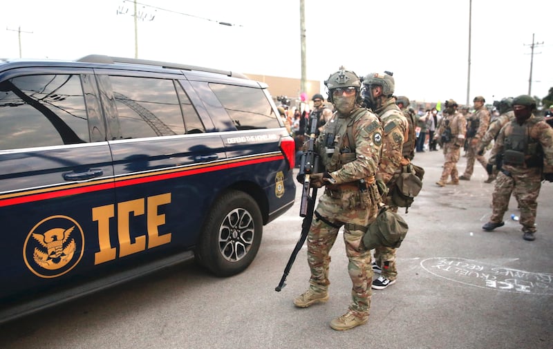 Immigration and Customs Enforcement (ICE) agents armed with less-lethal weapons gather outside an ICE processing center during a protest in Broadview, Illinois
