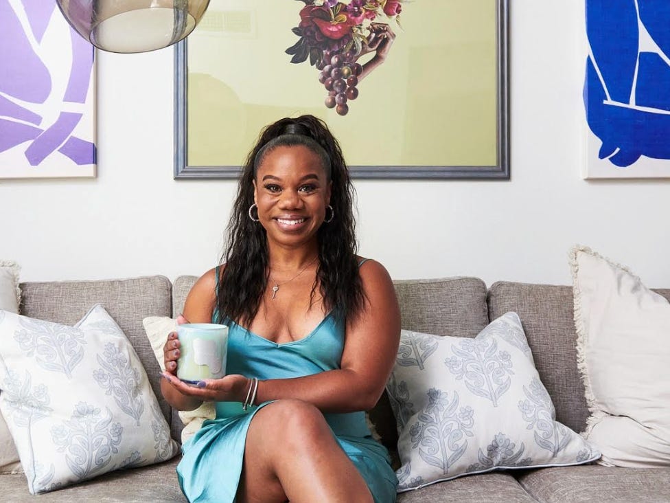 The writer posing on a couch in her home and holding up a candle.