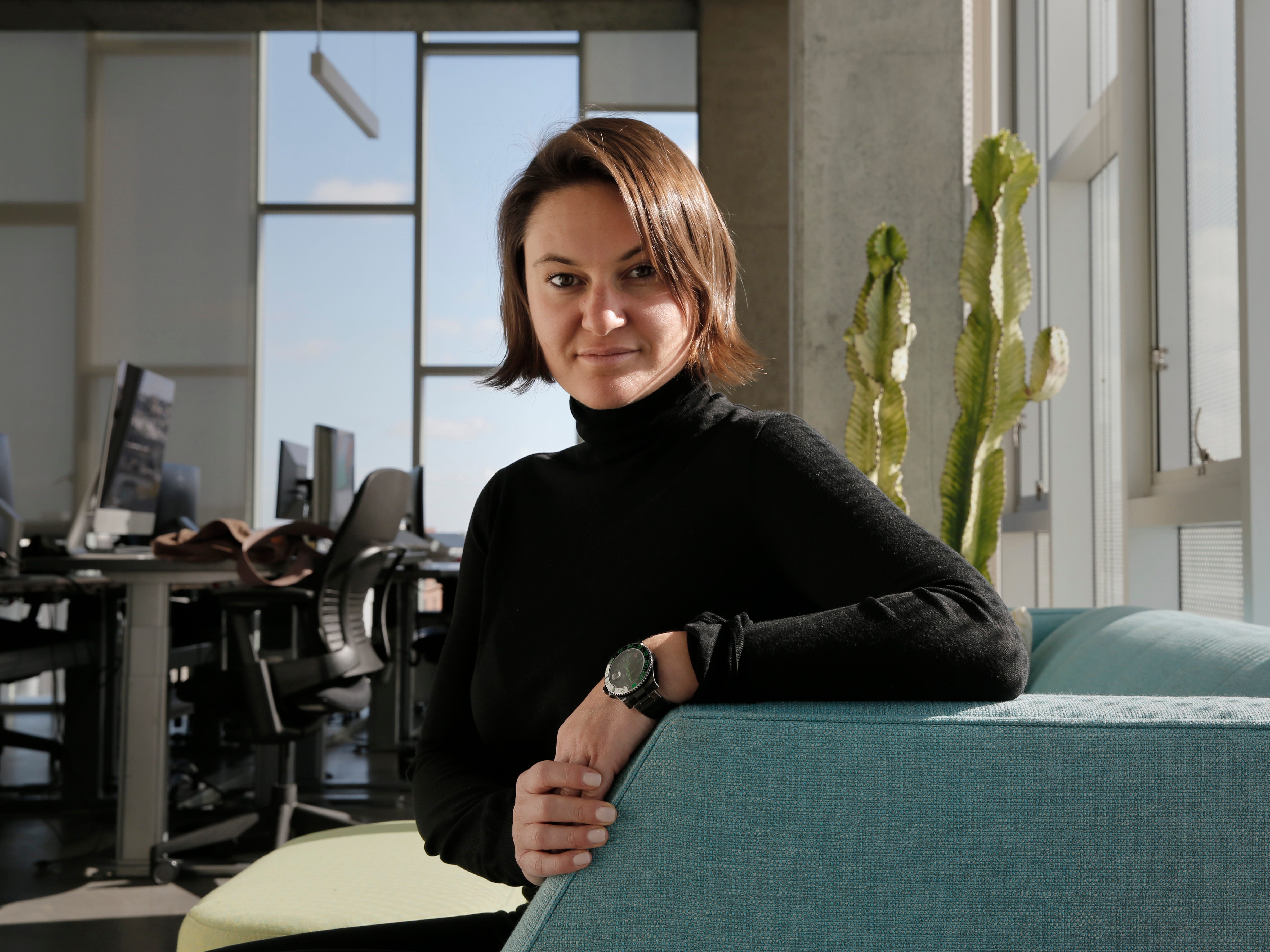 Eugenia Kuyda in a black turtleneck, sitting on a green couch.