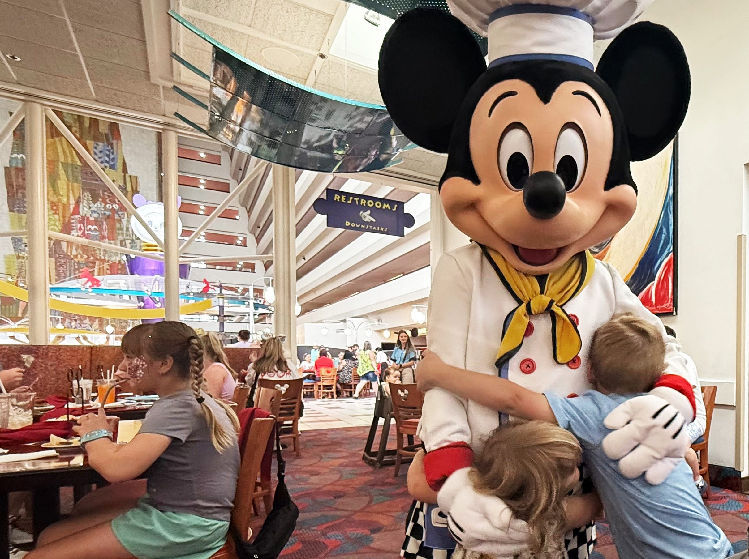 The author's children hug Mickey Mouse while dining at a character dinner.