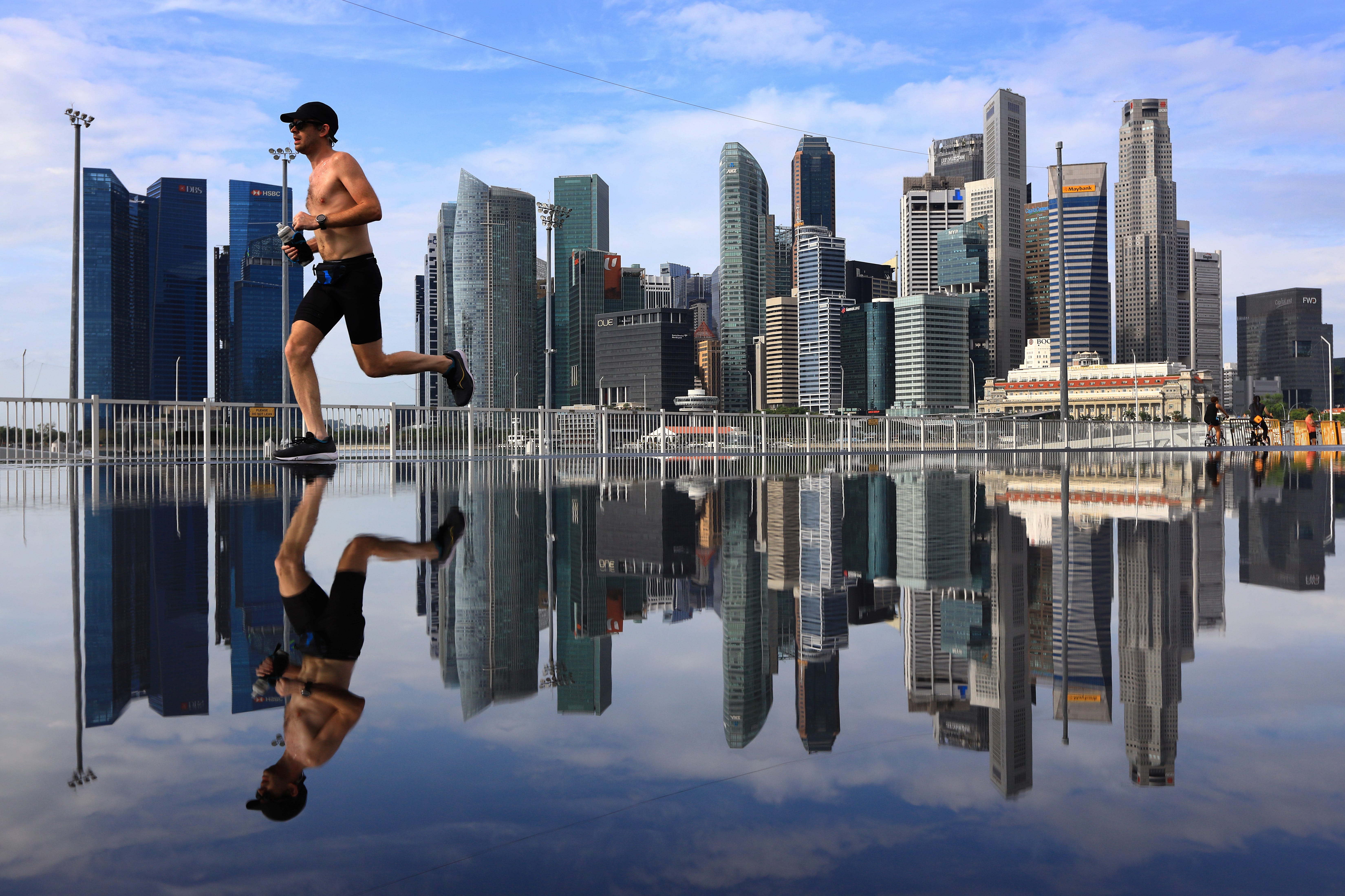 A man jogs along the riverfront with the city skyline pictured in the background at Marina Bay in Singapore, on February 5, 2022.