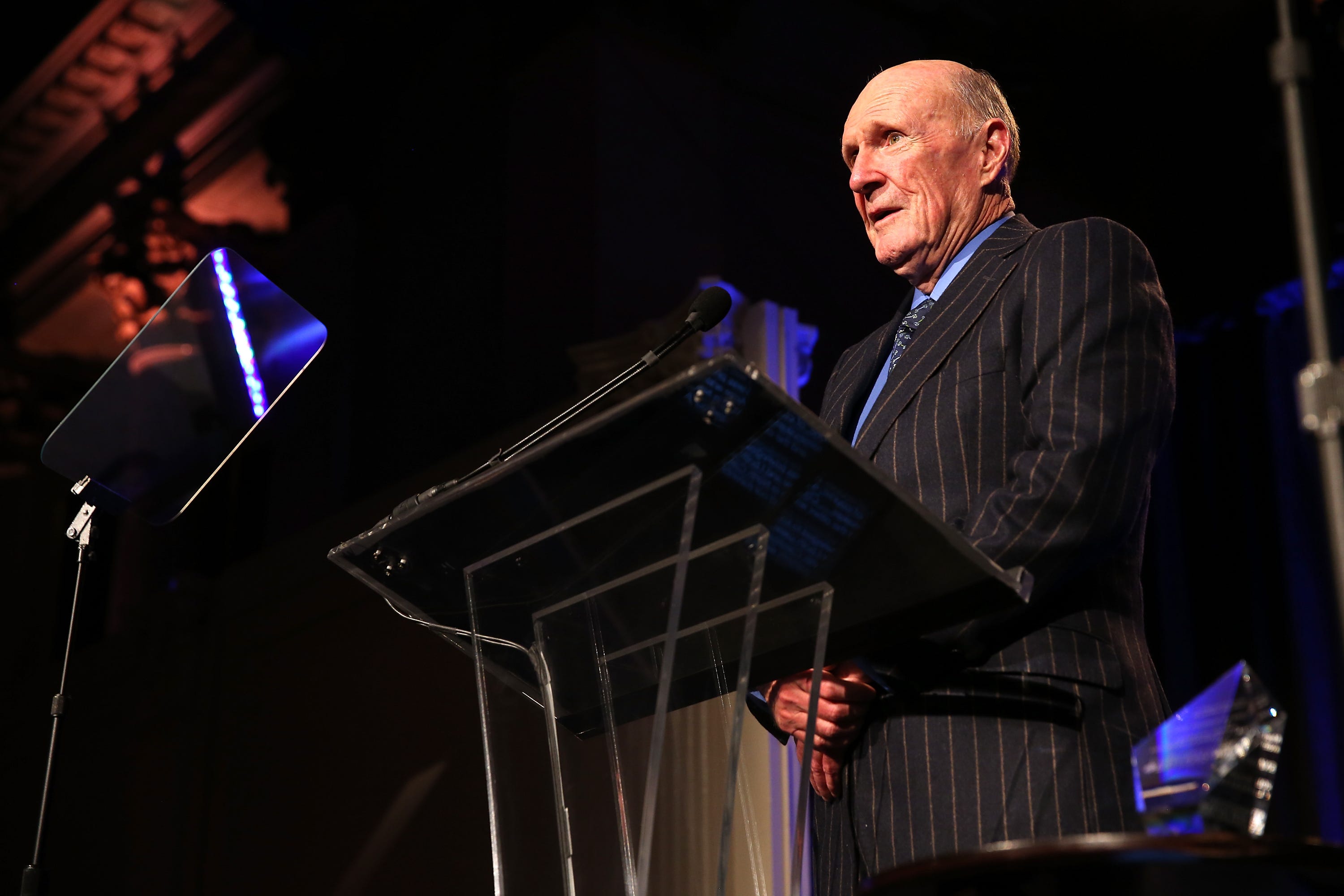 Julian Robertson speaking behind a podium in a suit