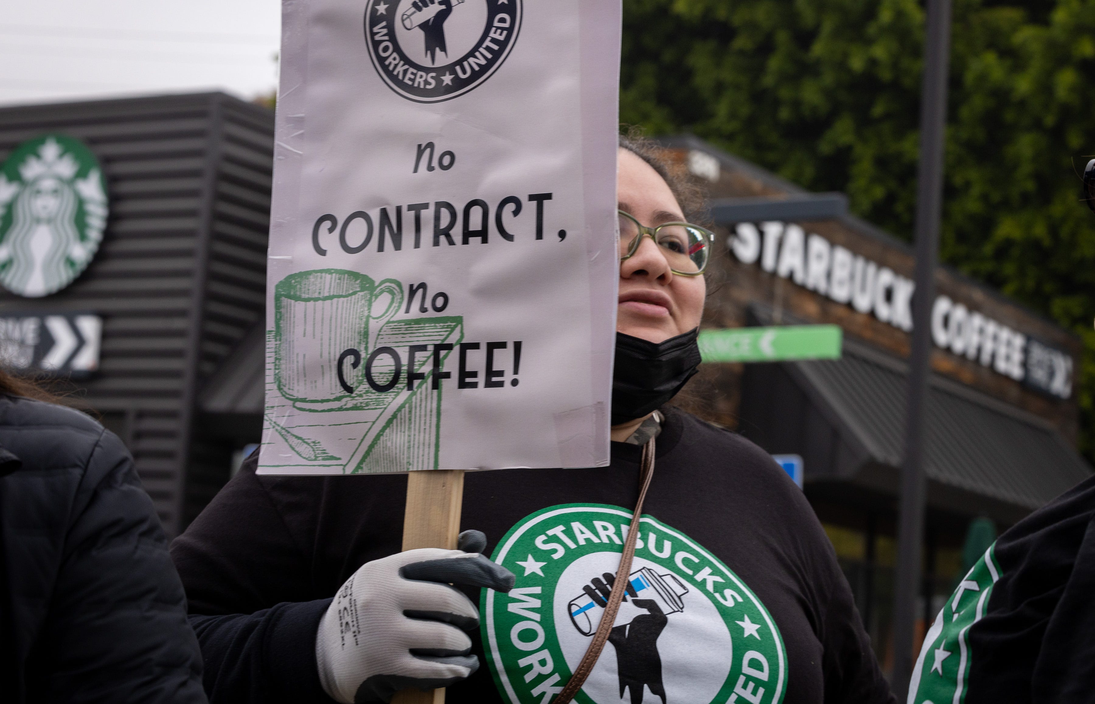 A Starbucks barista holds a picket sign during a strike in December 2024.