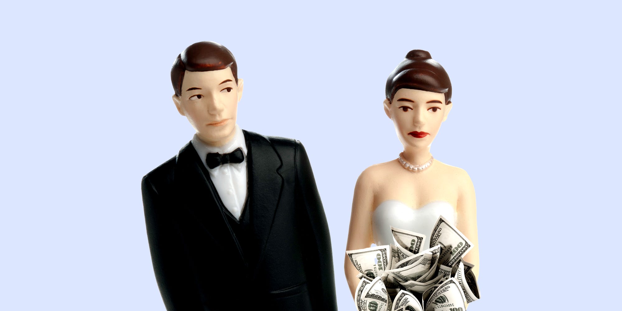 A male cake topper leaning away from a female cake topper holding a bouquet of money.