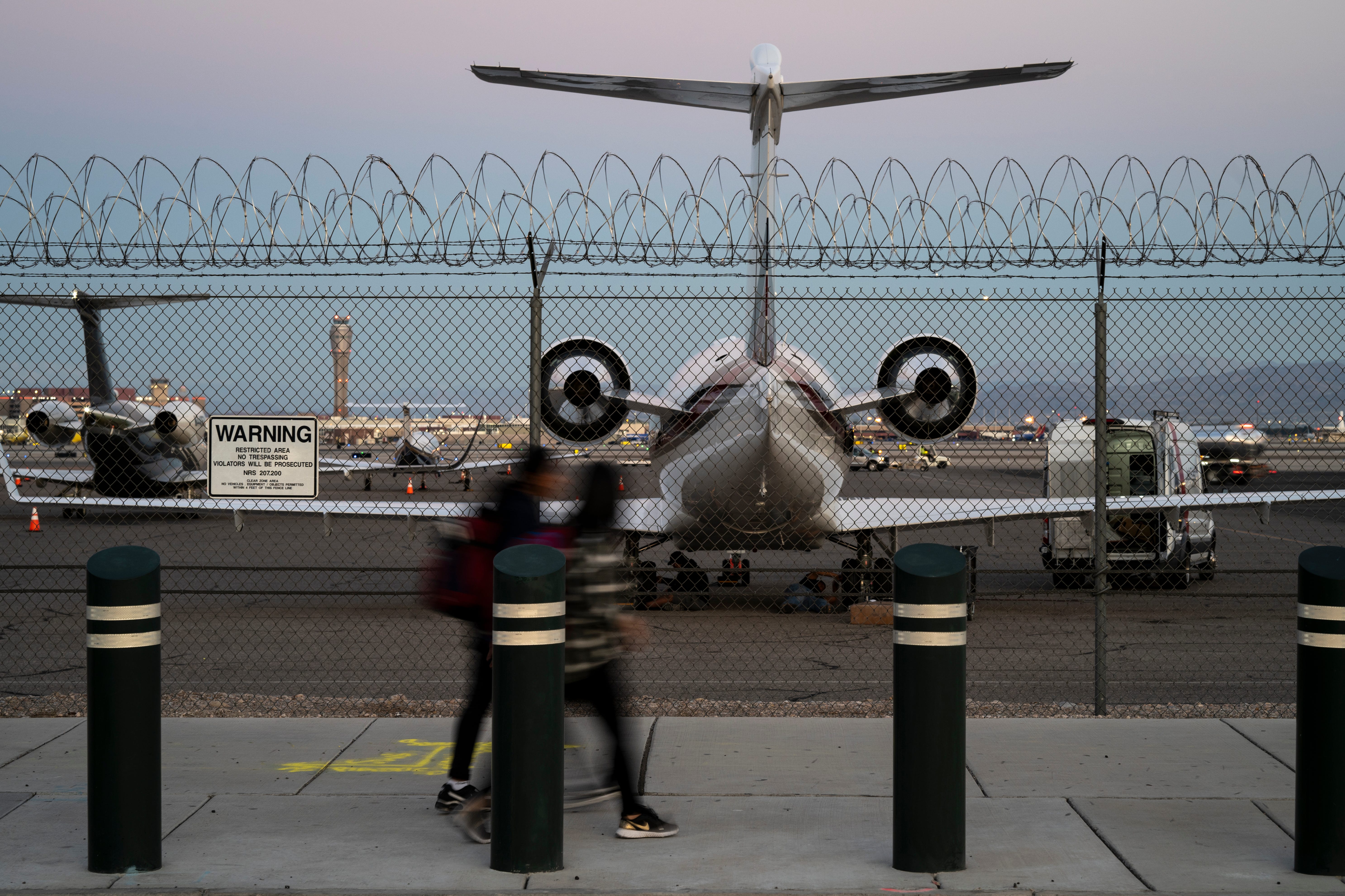 Private jets at Las Vegas airport with blurred people walking in front.