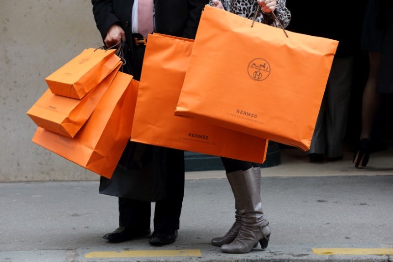 A couple walk with Hermes shopping bags as they leave a Hermes store in Paris, France, March 21, 2013.   REUTERS/Philippe Wojazer/File Photo