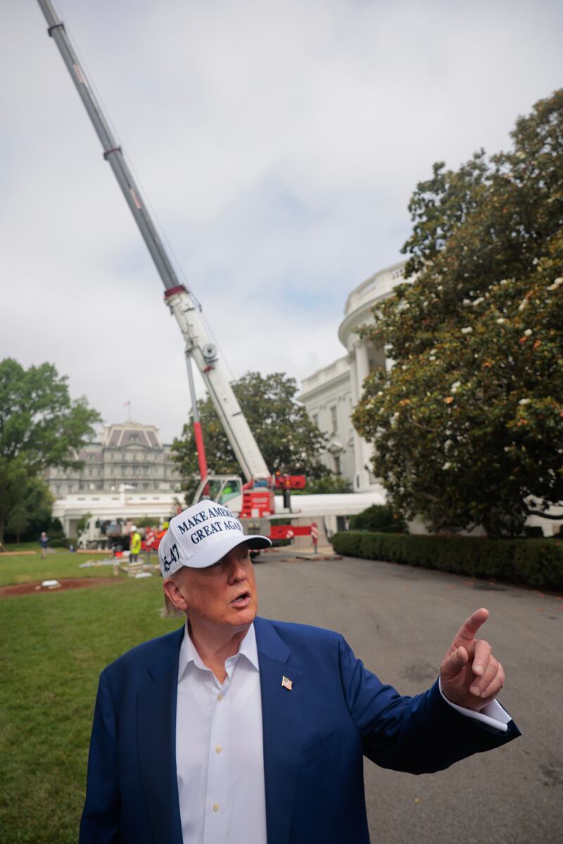 U.S. President Donald Trump talks to reporters as workers install a new flag pole on the South Lawn of the White House