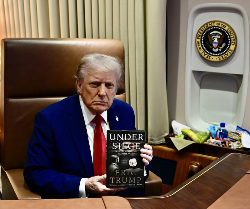 President Donald Trump poses with a copy of Eric Trump's new memoir, 'Under Siege.'