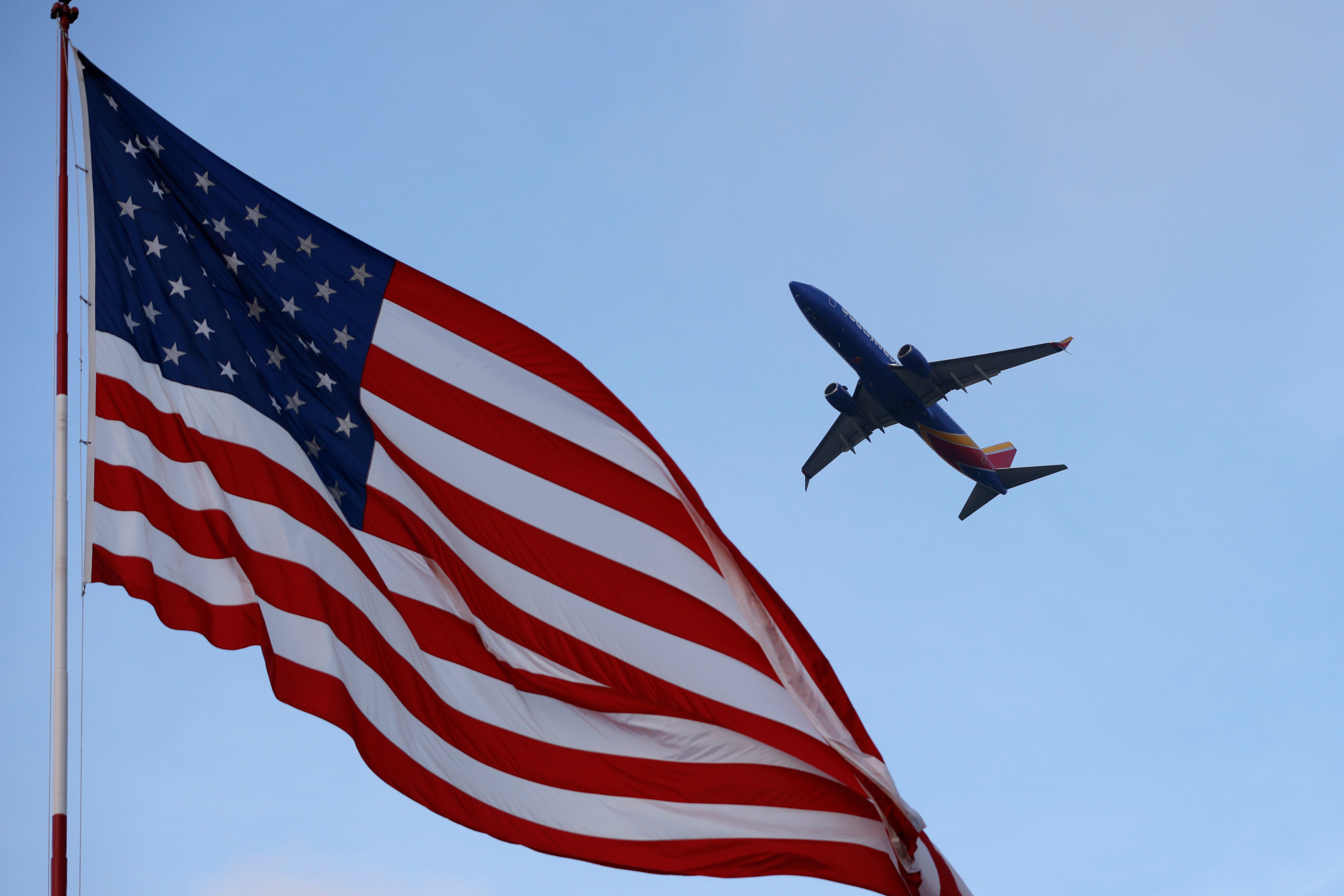 American flag with plane flying in background.