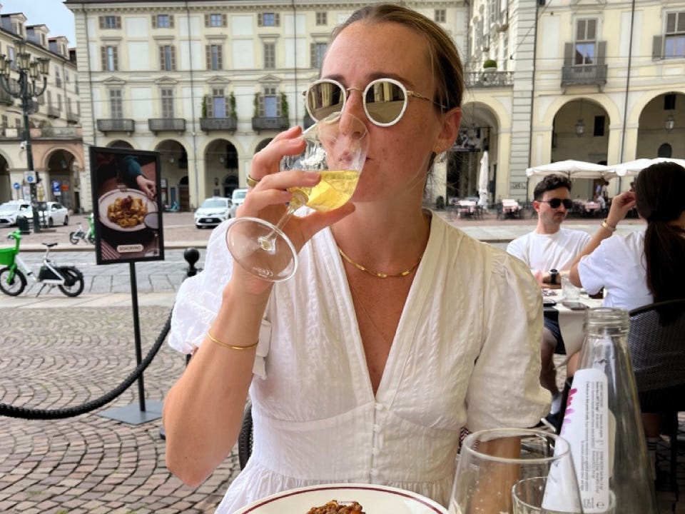 Author Rachel Hosie sipping wine in Turin with bowl of pasta in front of her