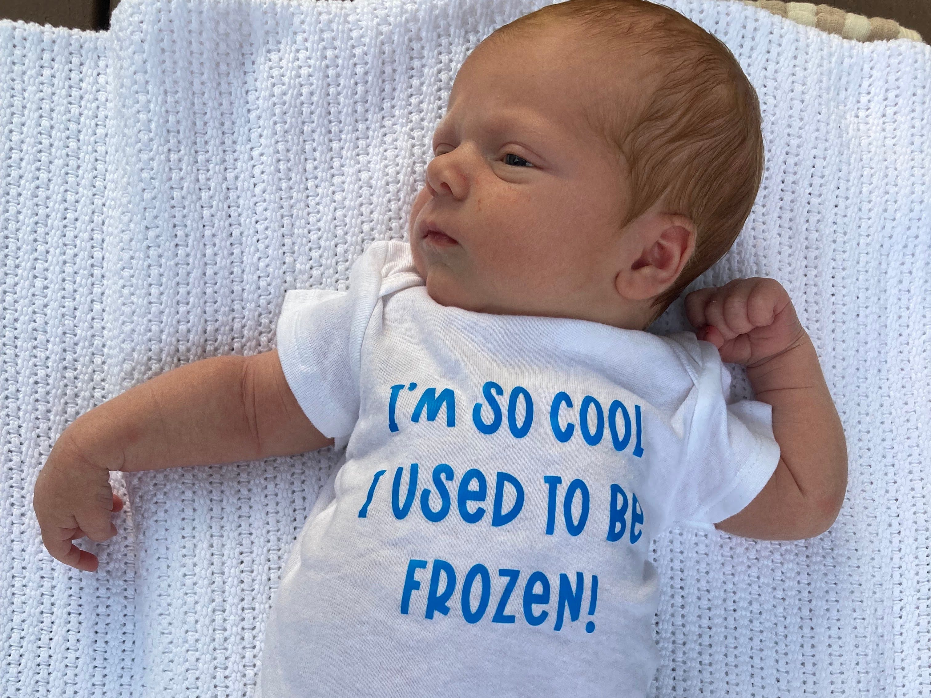 A baby wearing a onesie with words on it