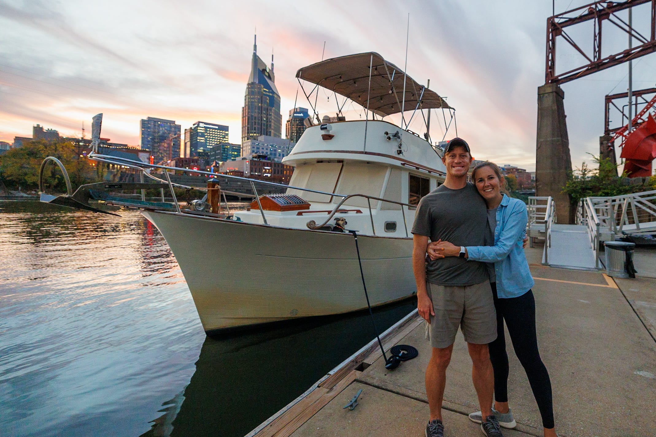 A couple posing in front of a boat.