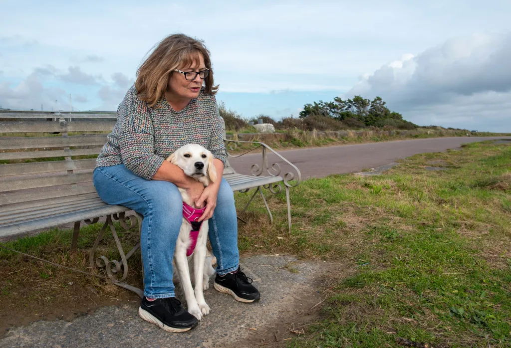 Upset woman with her golden retriever dog sitting on a park bench.