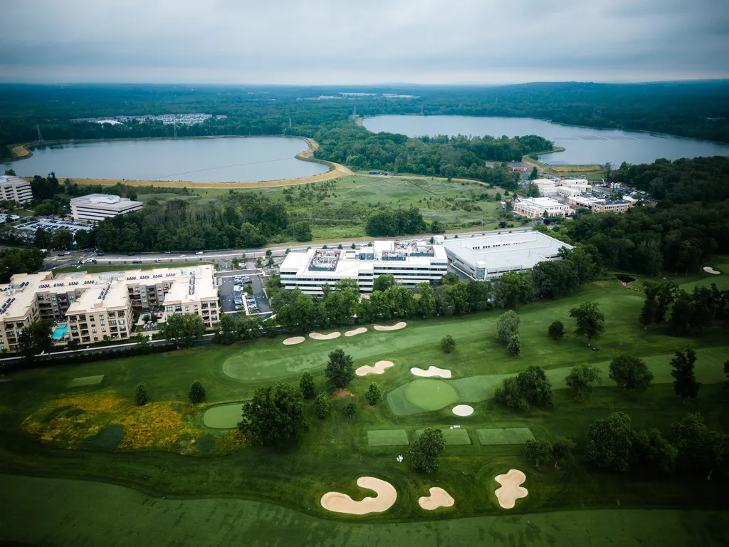 Aerial drone view of a golf course, residential buildings, commercial properties, and two lakes in Millburn, New Jersey.