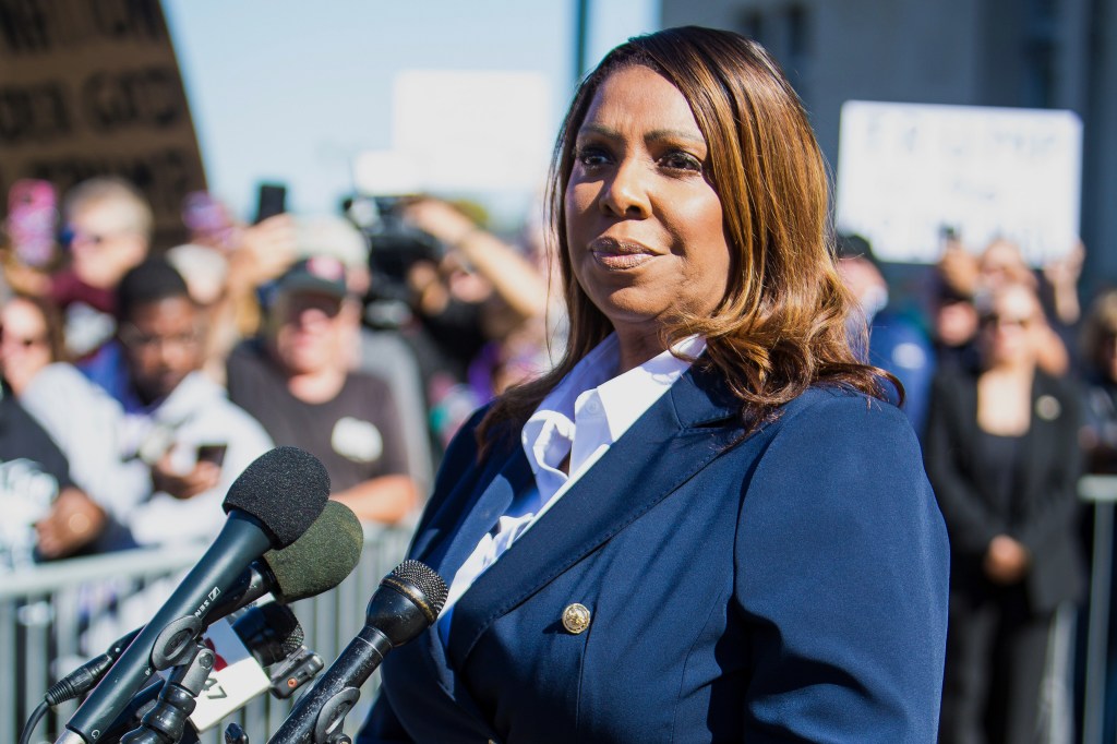 New York Attorney General Letitia James speaking at a podium with microphones in front of a crowd.
