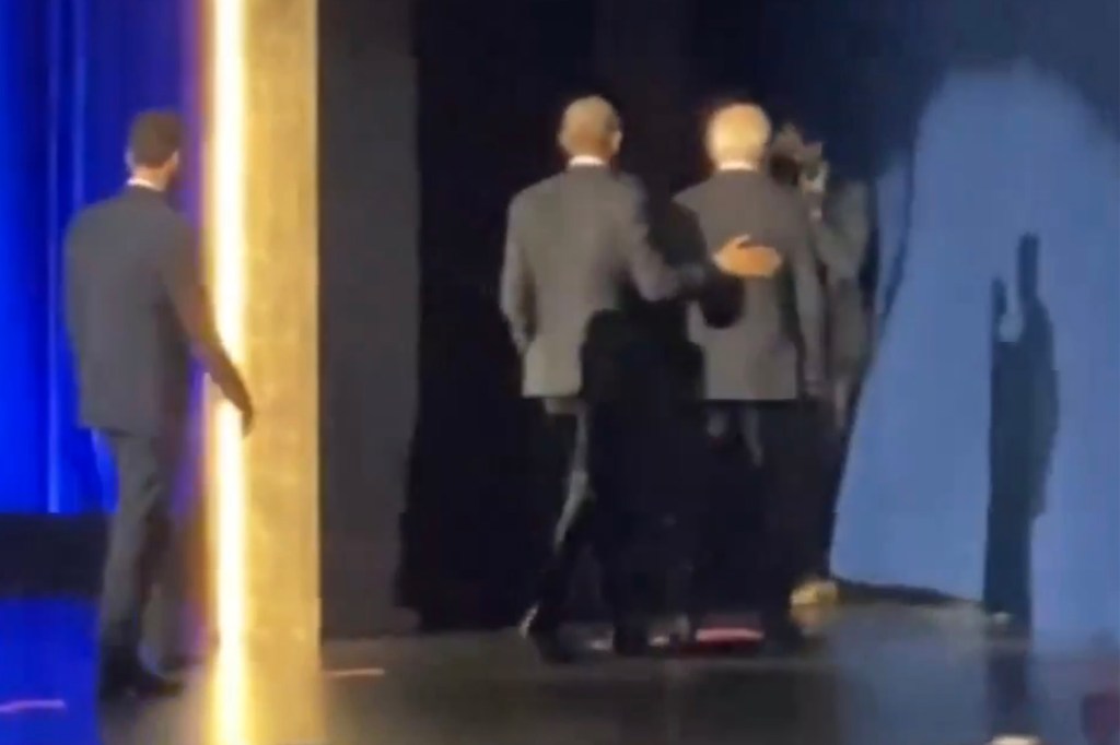 Former President Barack Obama leads President Joe Biden off the stage during an event.