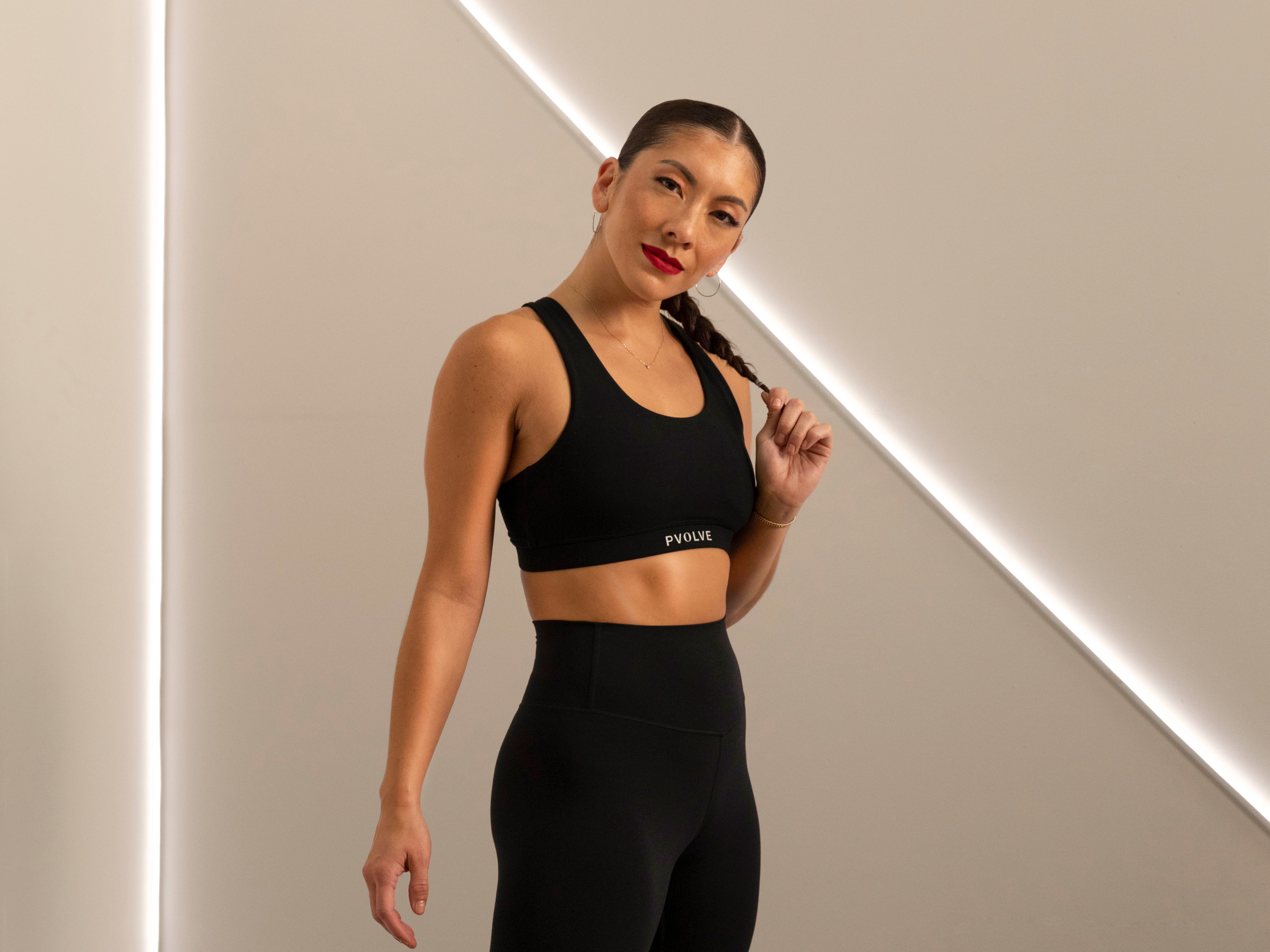 A portrait photo of personal trainer Dani Coleman in workout clothes against a dramatically lit background